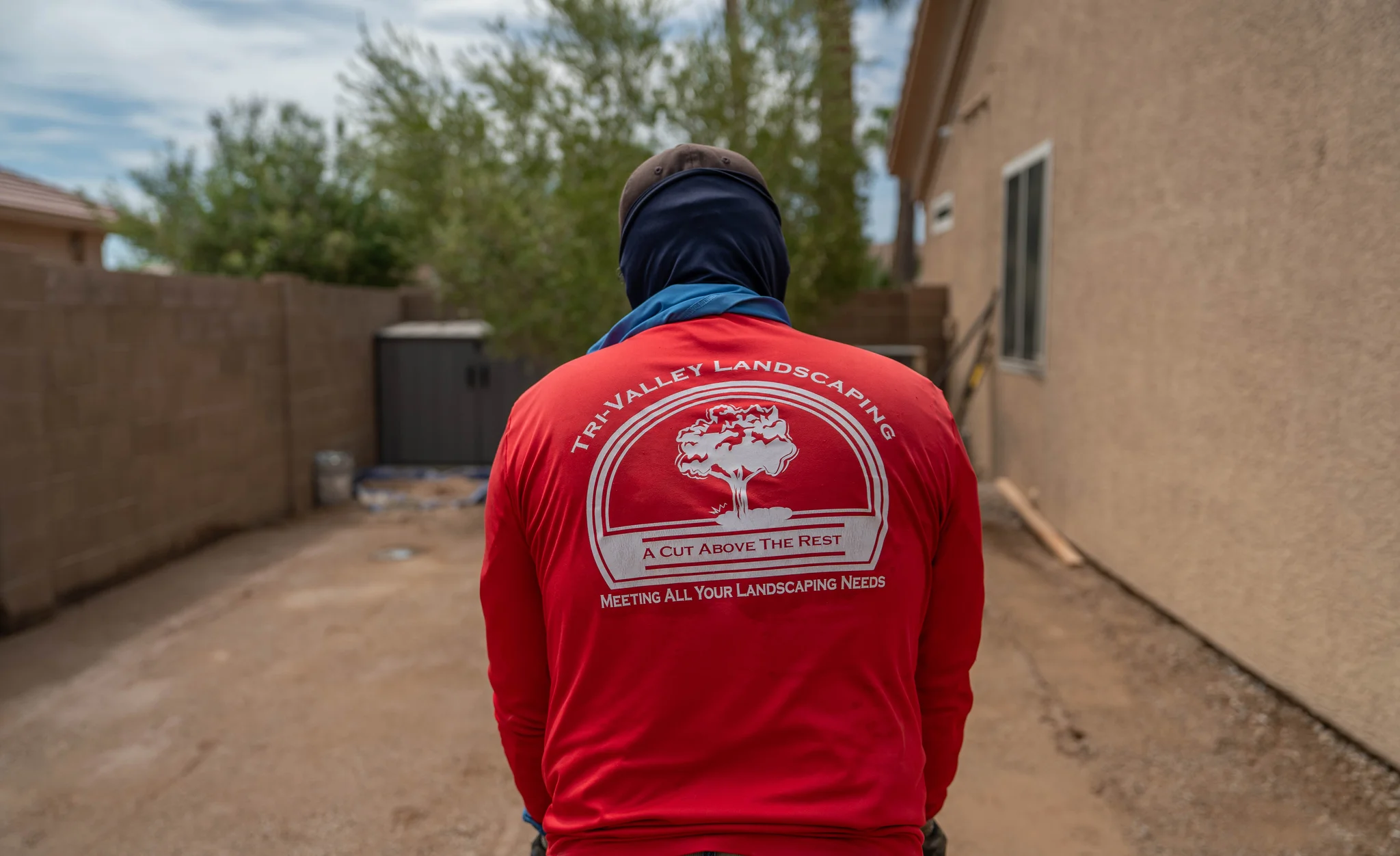Landscaper wearing red Tri-Valley Landscaping shirt in residential yard