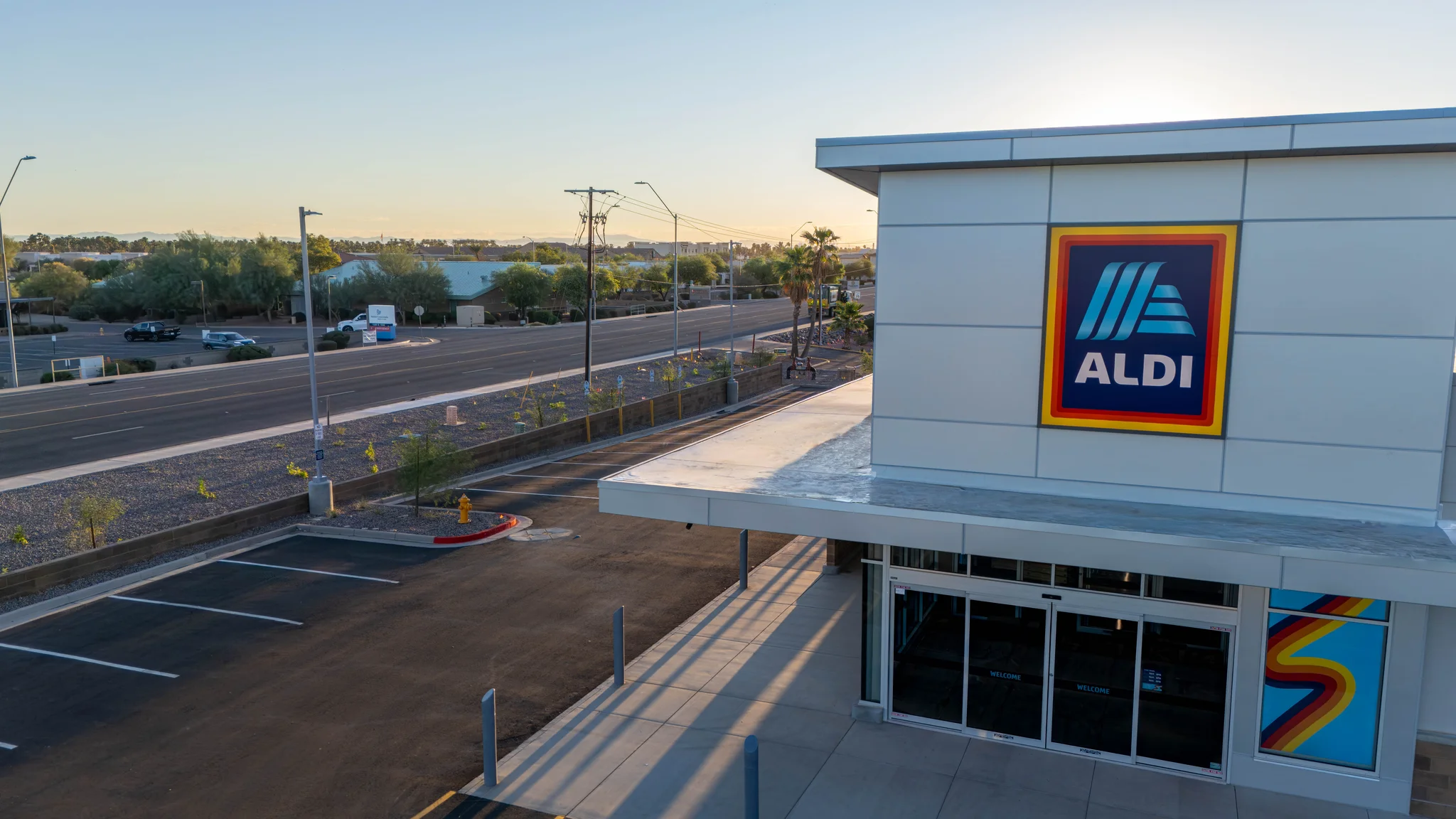 ALDI store entrance beside an empty parking lot at sunset