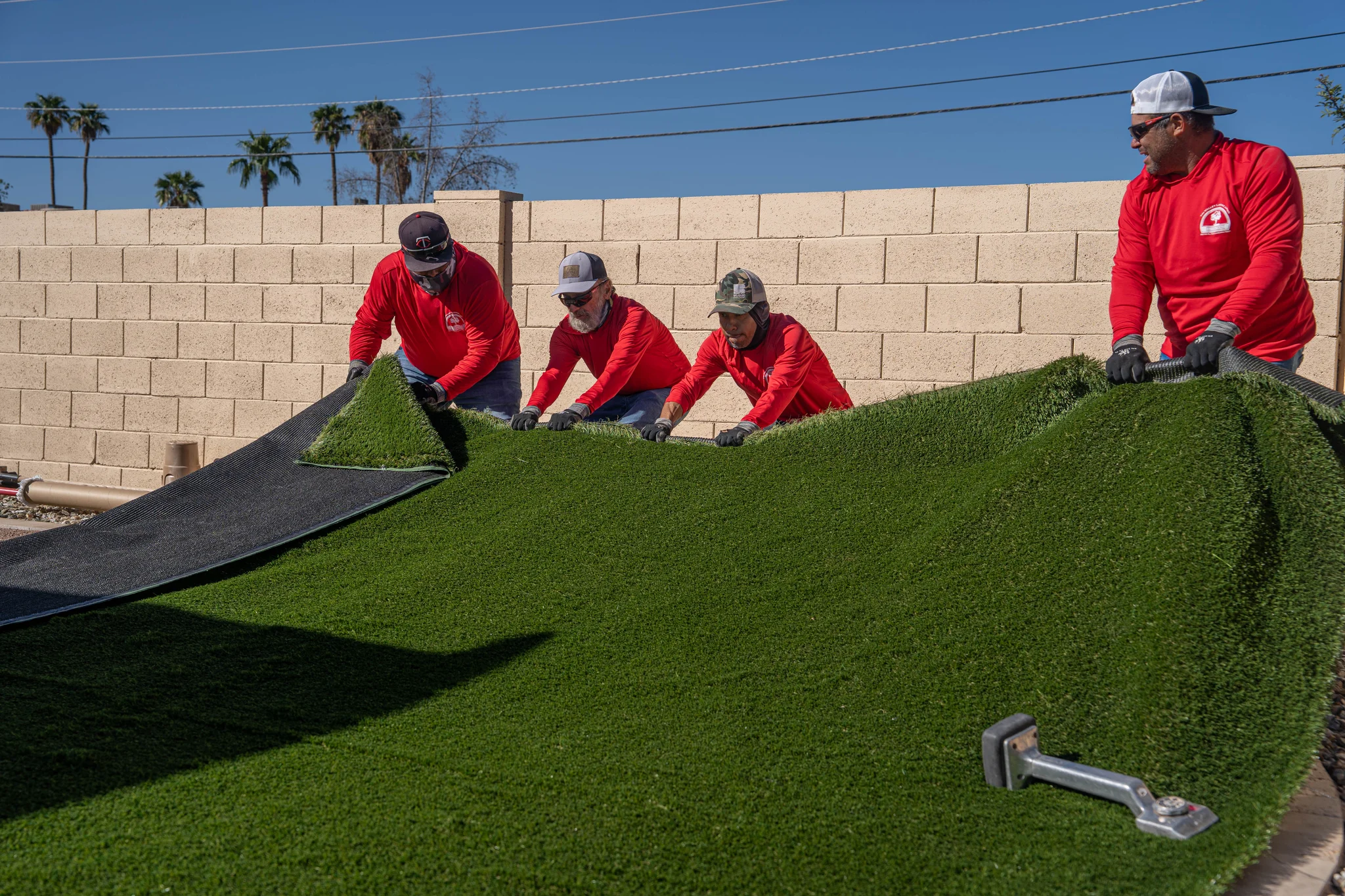 Crew installing rolls of artificial turf outdoors