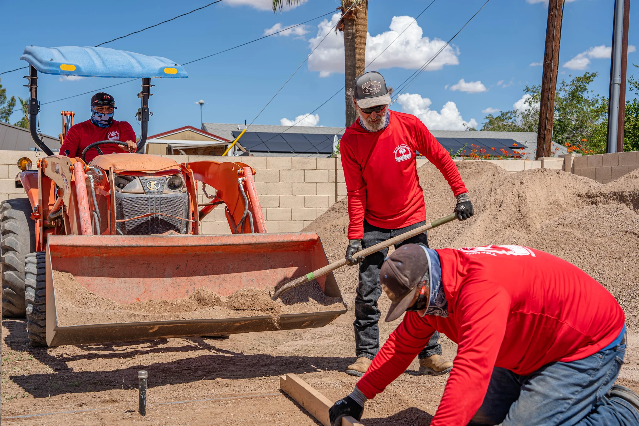 Workers spread gravel beside a tractor at construction site