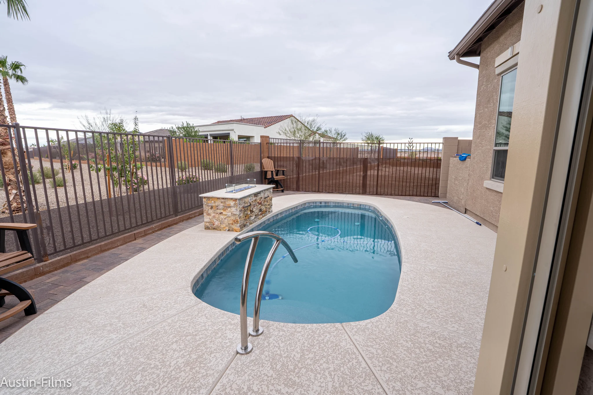 Compact backyard pool with fire pit and fenced desert landscaping
