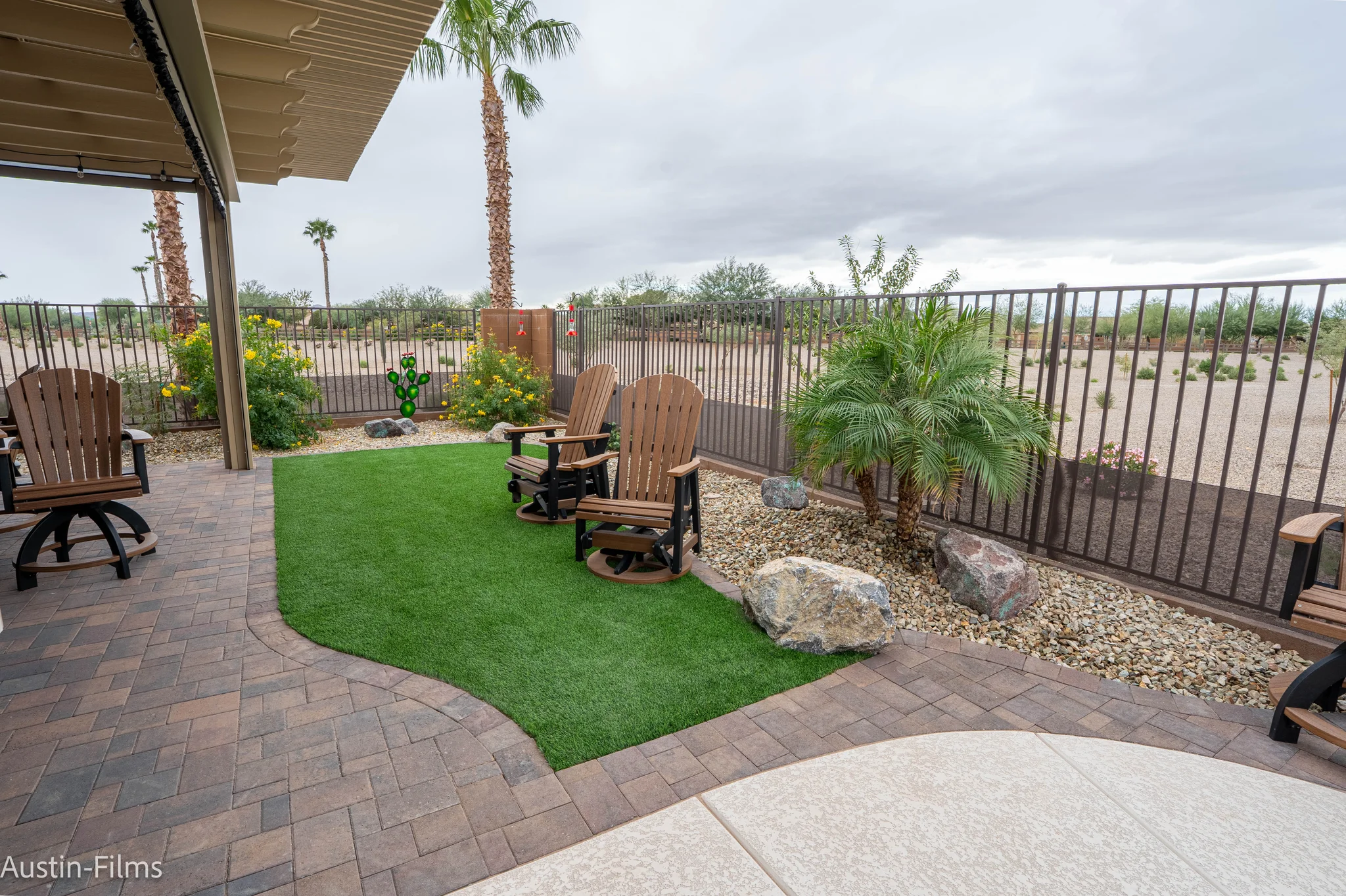 Covered desert patio with Adirondack chairs and palm landscaping