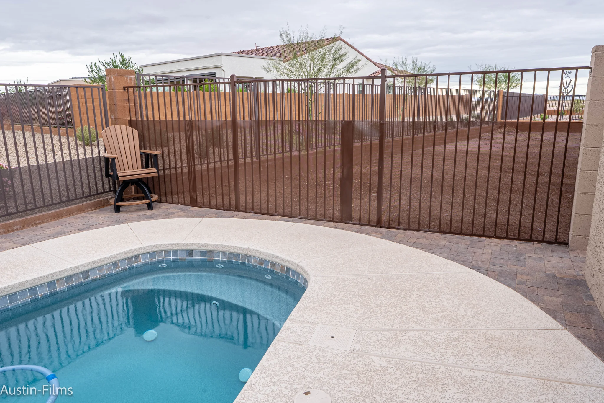 Backyard pool patio with chair and privacy fence