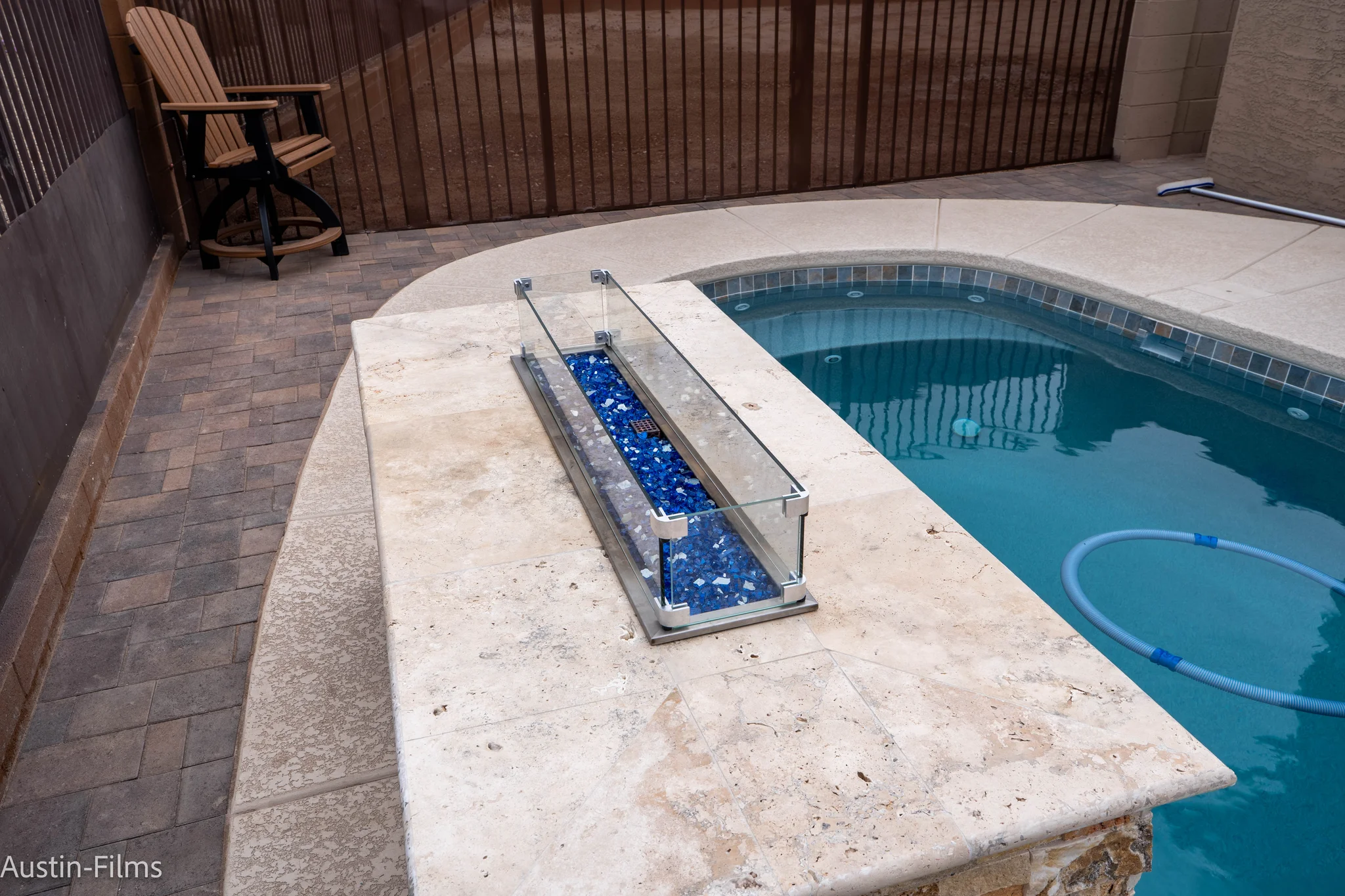 Blue glass fire feature beside backyard swimming pool