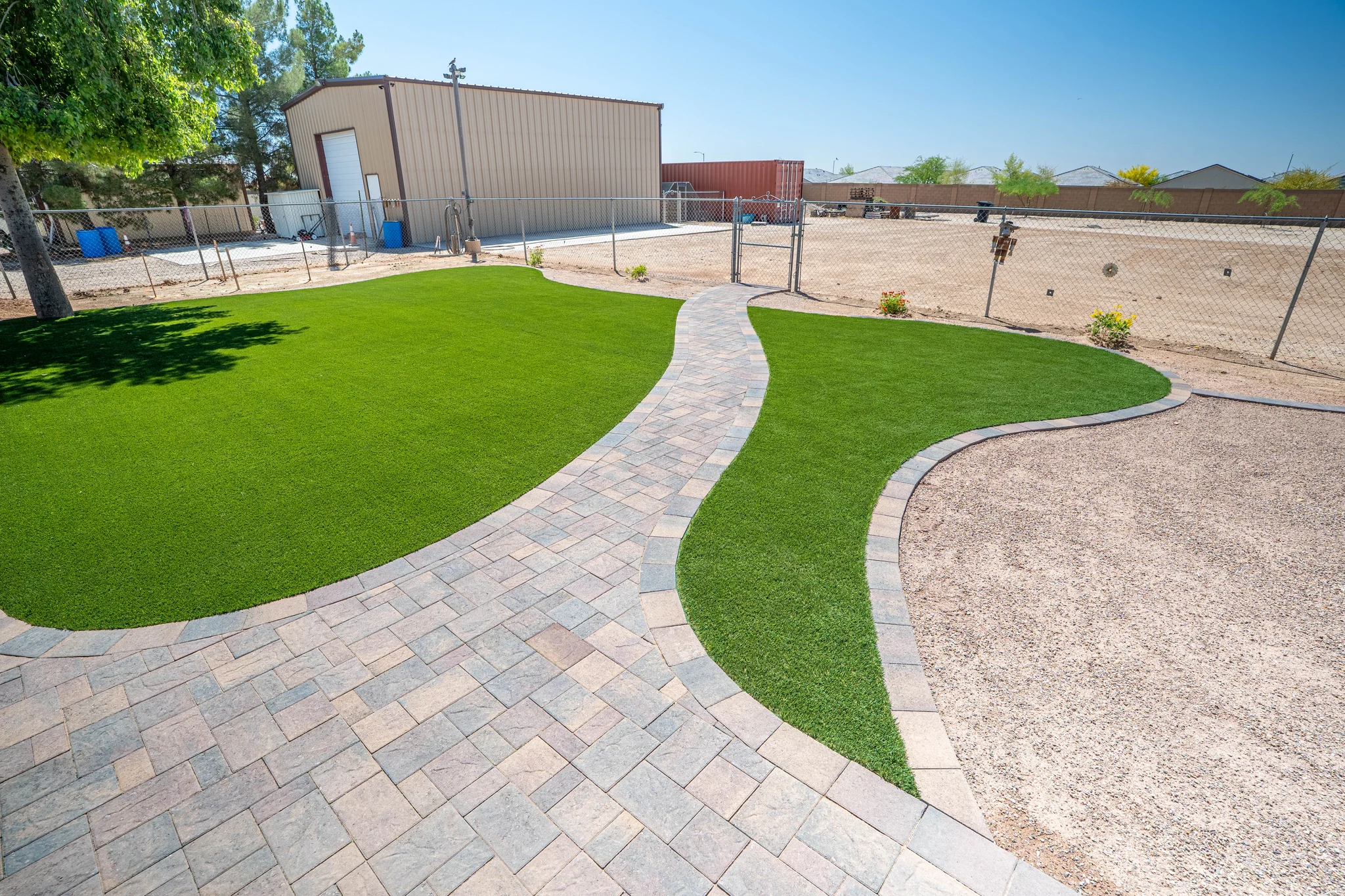 Curved paver path through artificial turf backyard