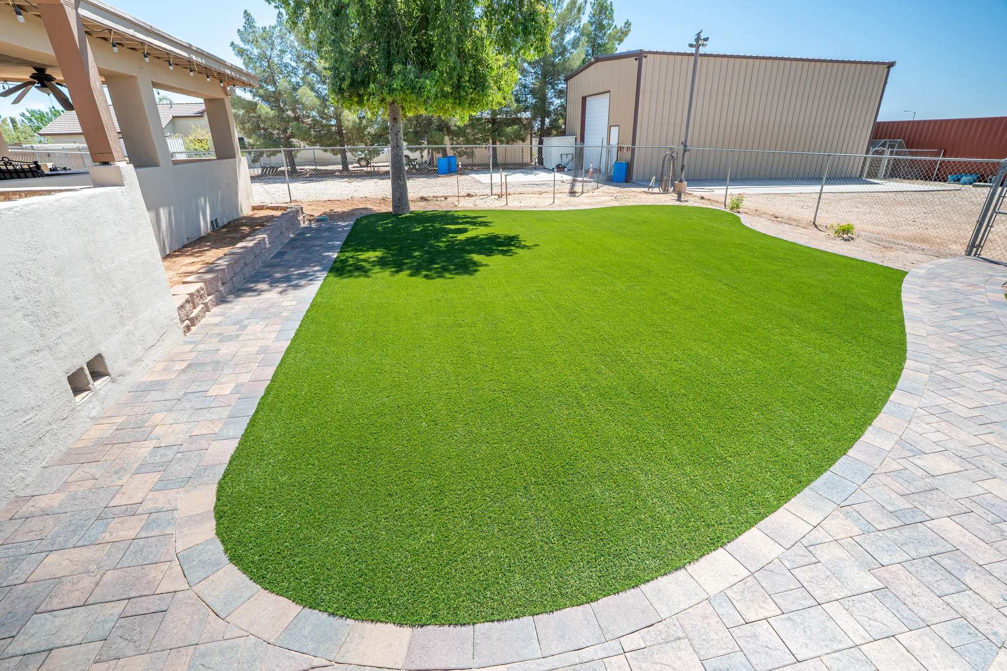 Artificial turf lawn bordered by curved stone pavers