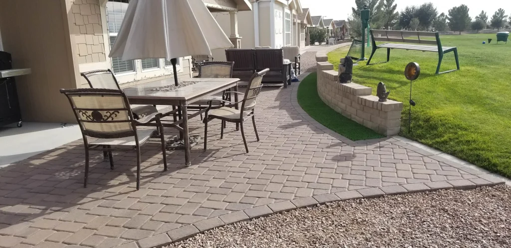 Paver patio with umbrella table beside landscaped backyard