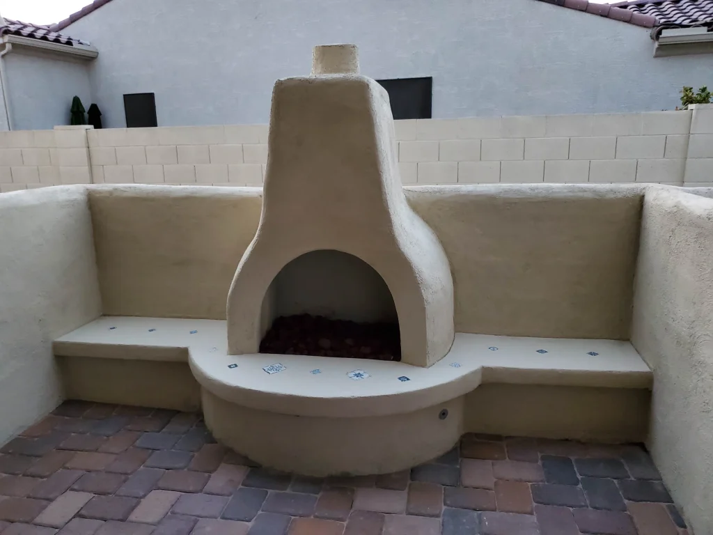Outdoor stucco fireplace with tiled bench seating