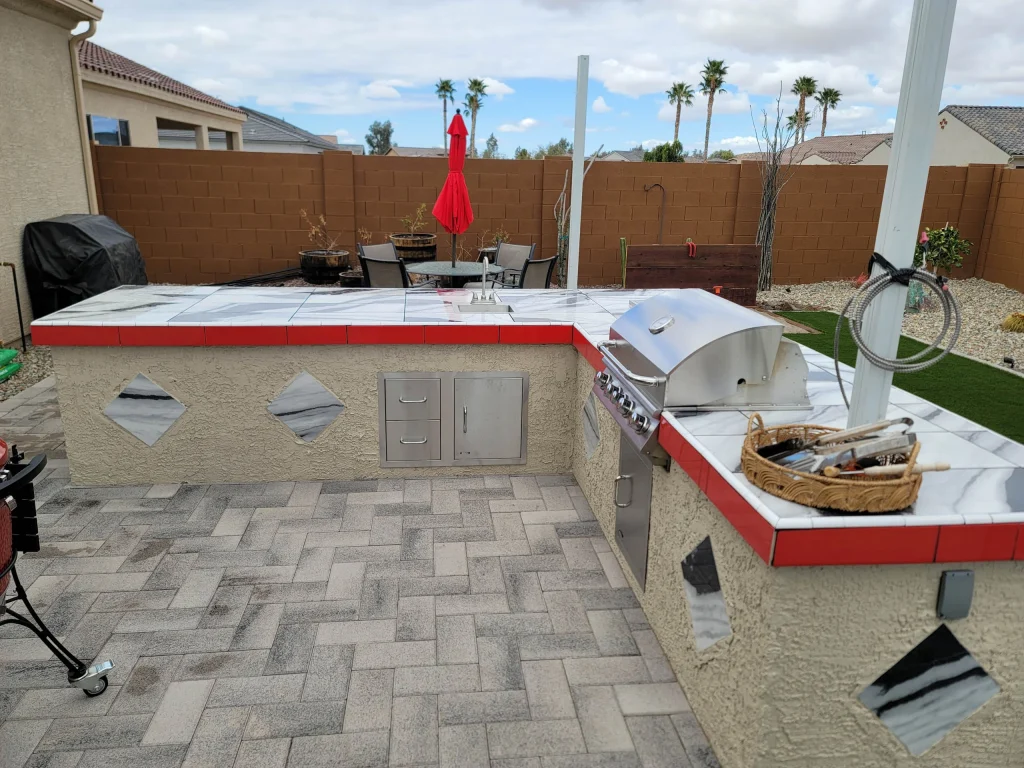 Backyard outdoor kitchen with grill, tiled counters, and patio seating