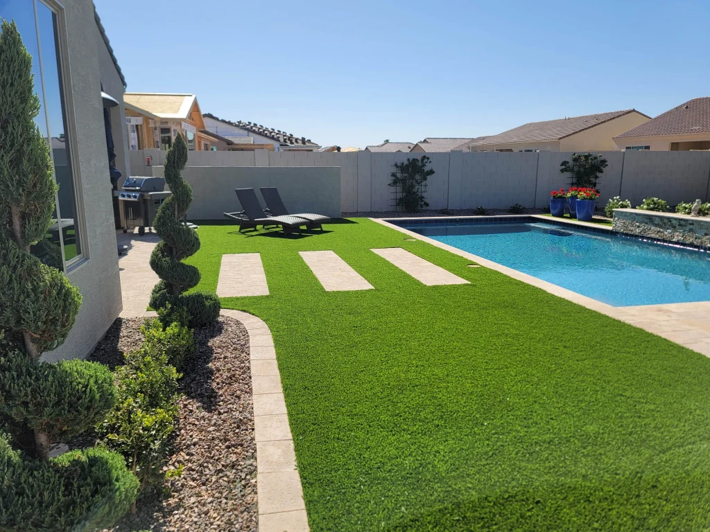 Modern backyard pool with artificial turf and lounge chairs