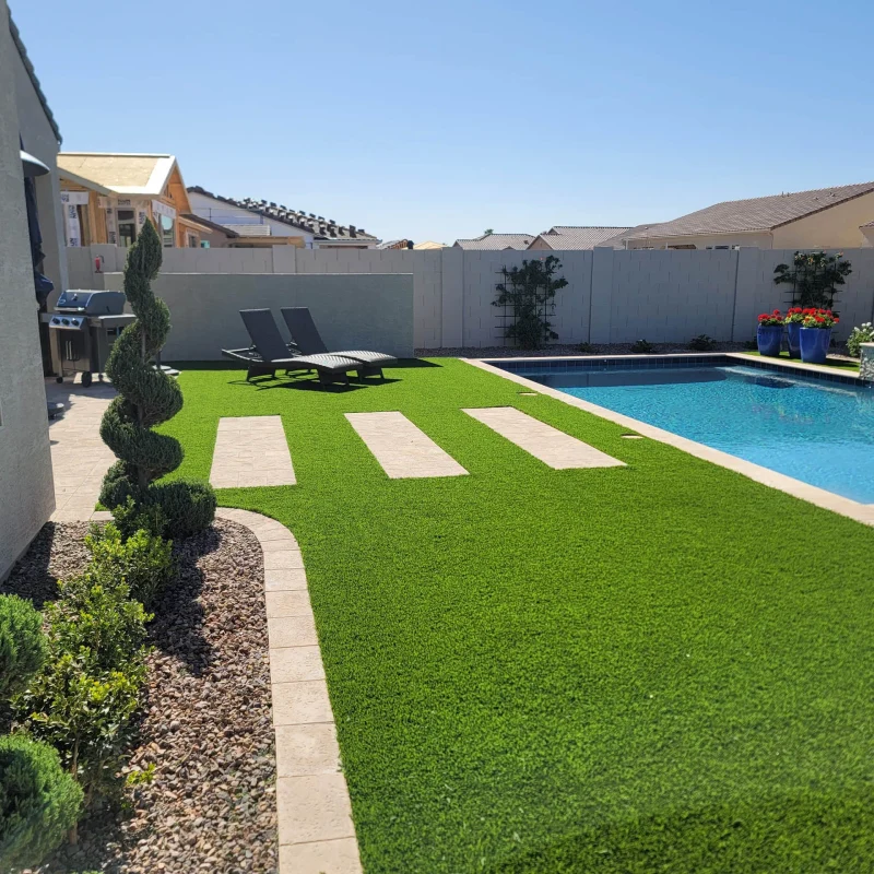 Sunny backyard pool with artificial turf and lounge chairs
