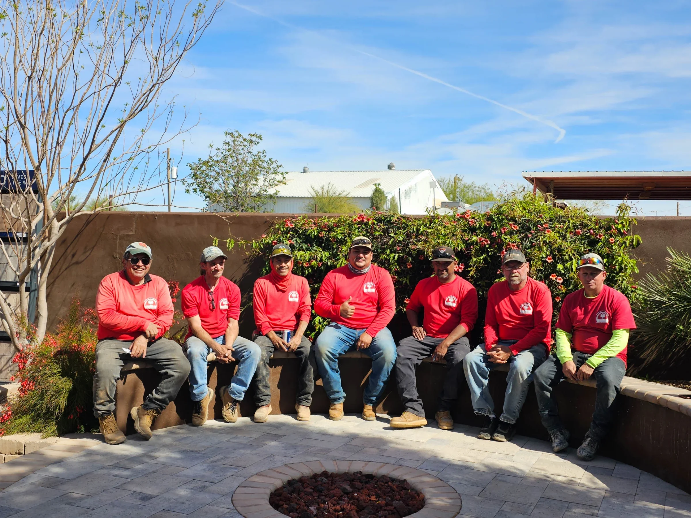 Seven workers in red shirts sit in landscaped courtyard