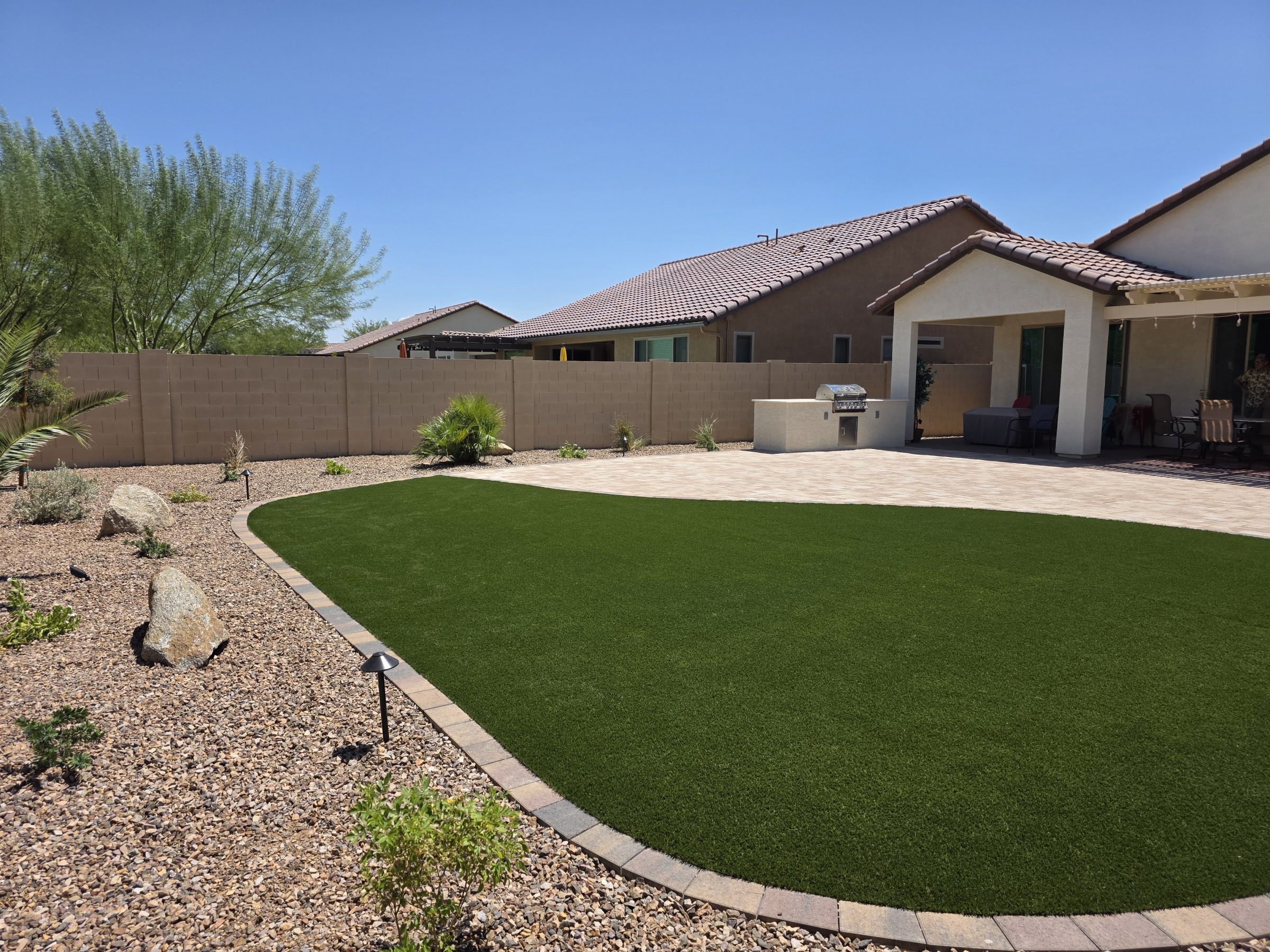 Desert backyard with artificial turf, patio, and outdoor grill
