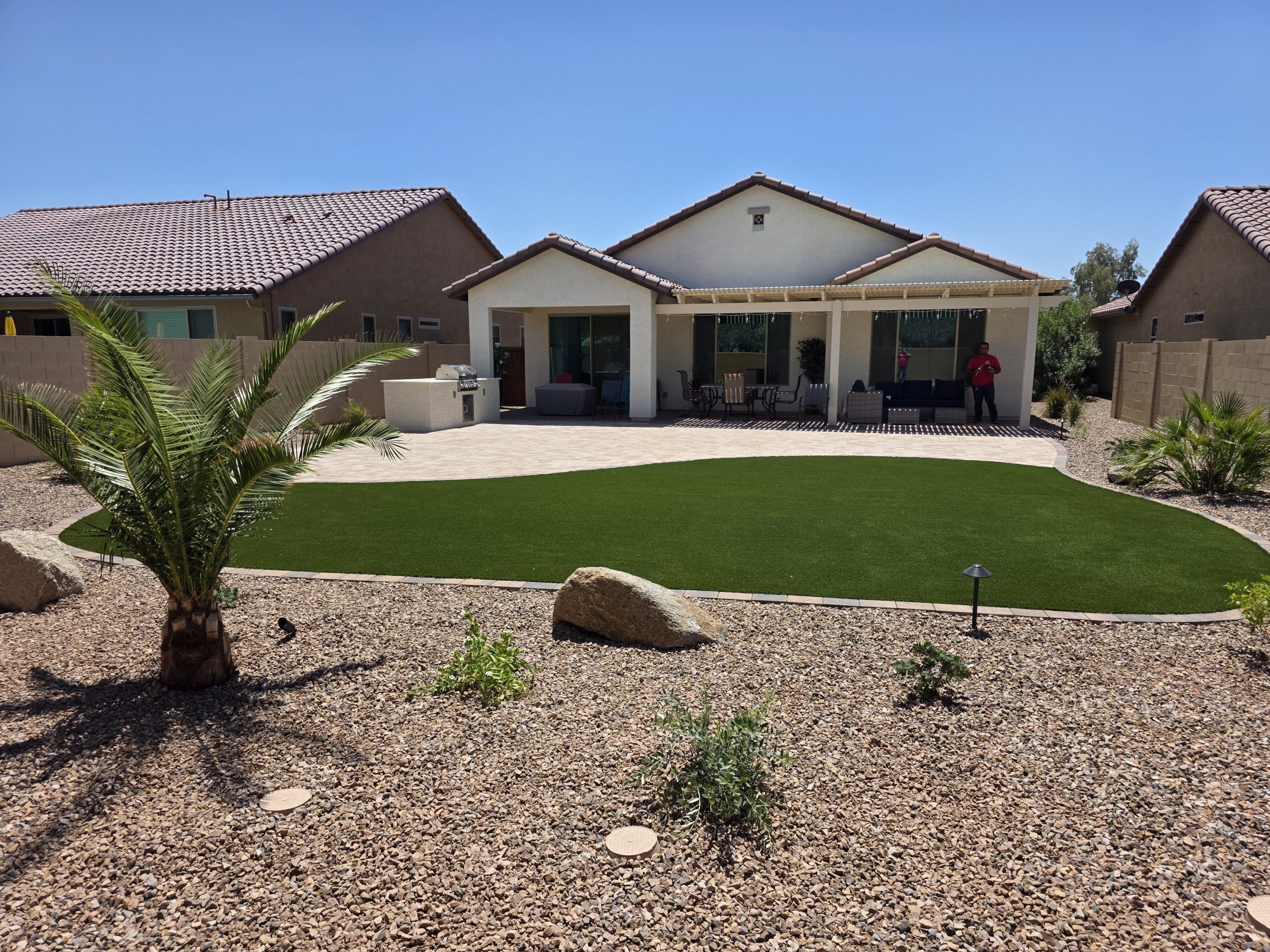 Desert backyard with artificial turf, patio, and covered seating