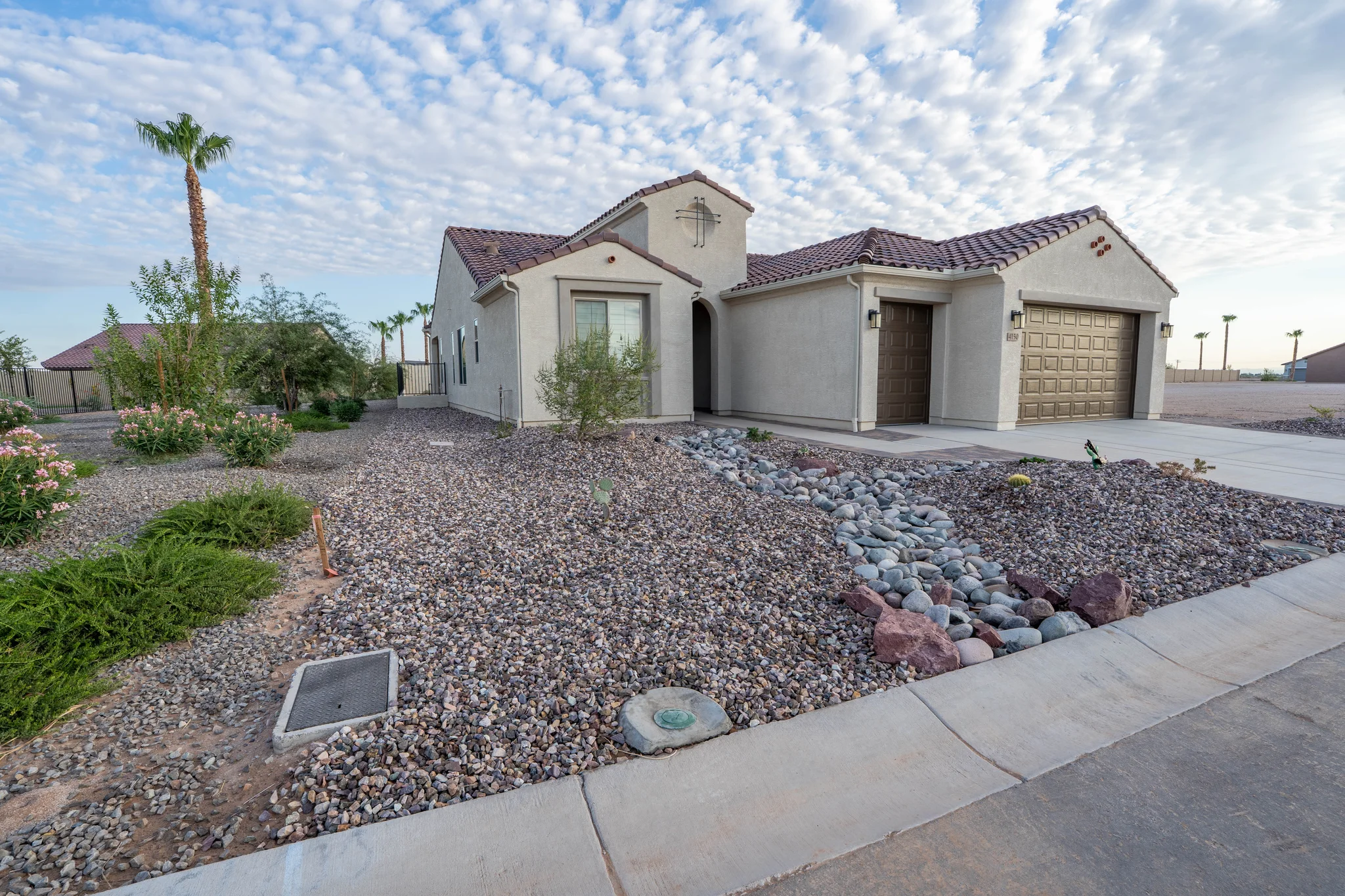 Desert landscaped stucco home with tiled roof and garage