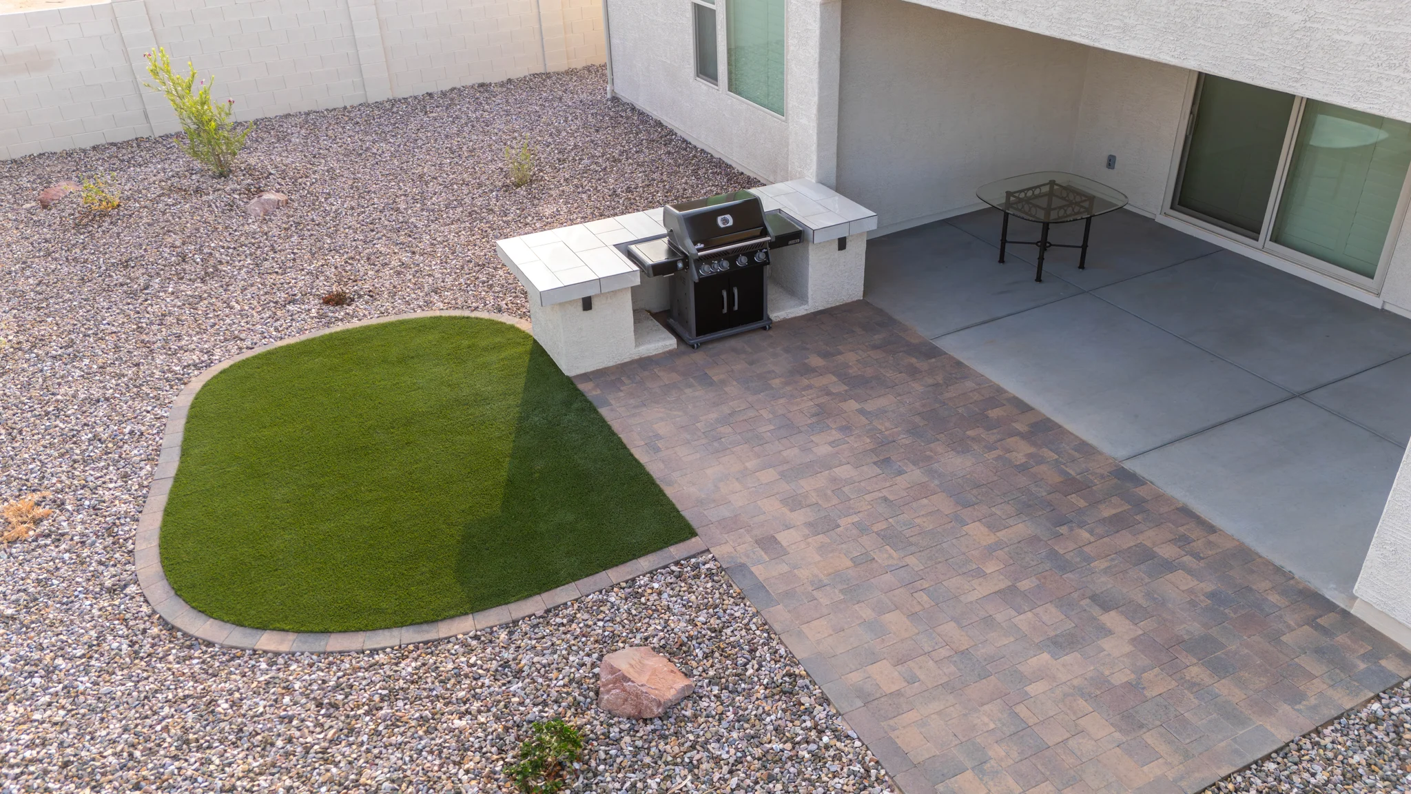 Desert backyard patio with grill, artificial turf, and pavers