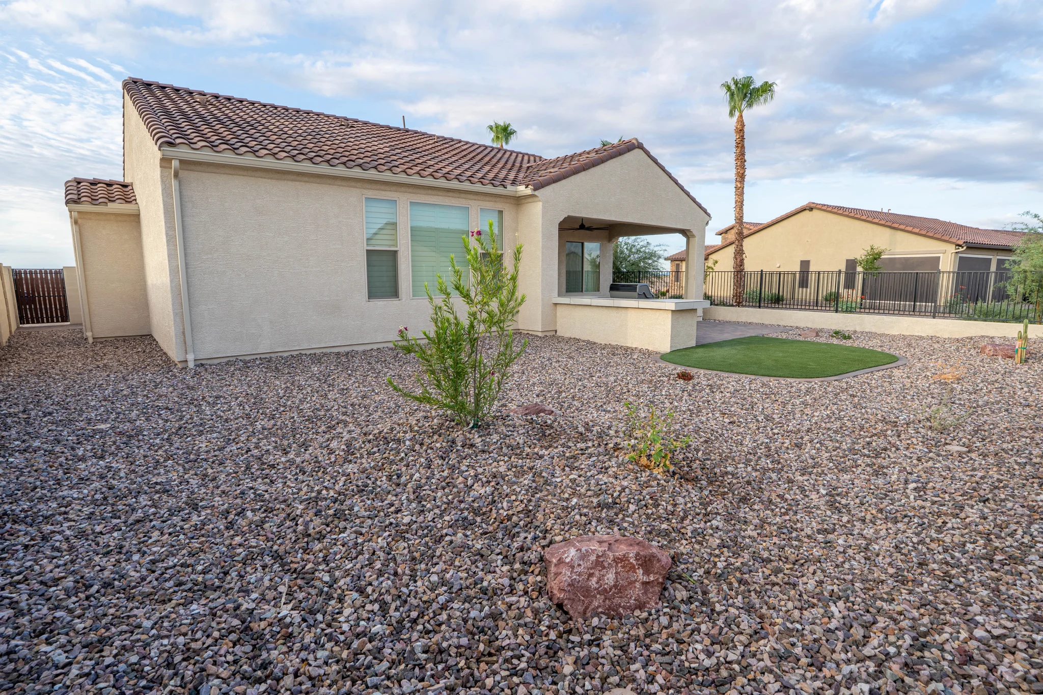 Desert backyard with covered patio, grill, and artificial turf