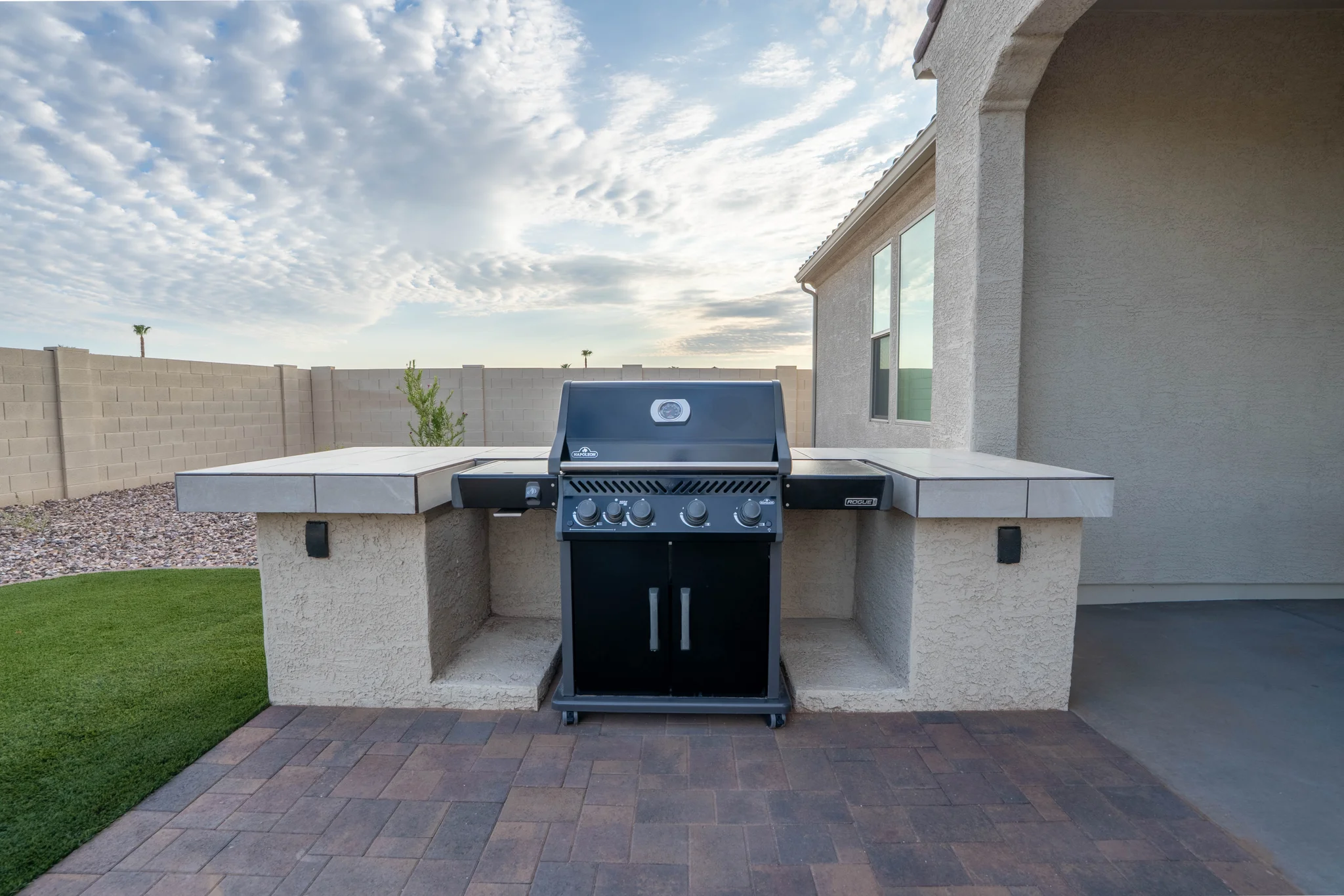 Gas grill between tiled outdoor counters on covered patio