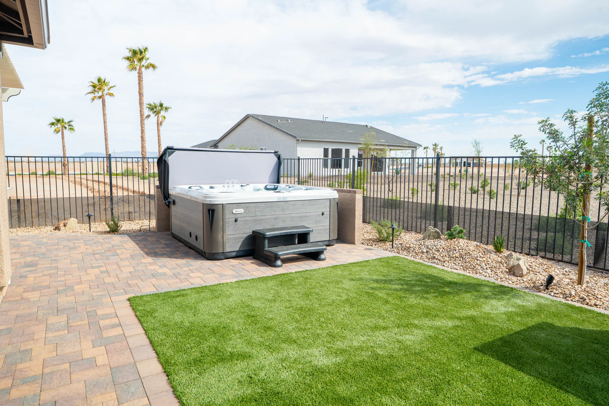 Backyard hot tub beside lawn and palm trees