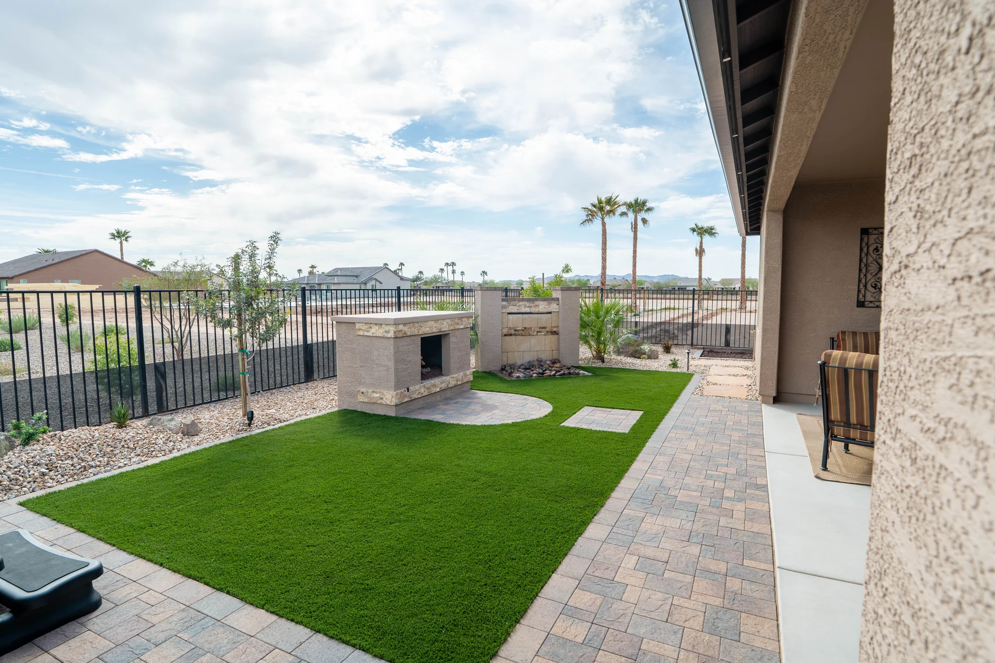 Landscaped backyard patio with fireplace, turf, and mountain views