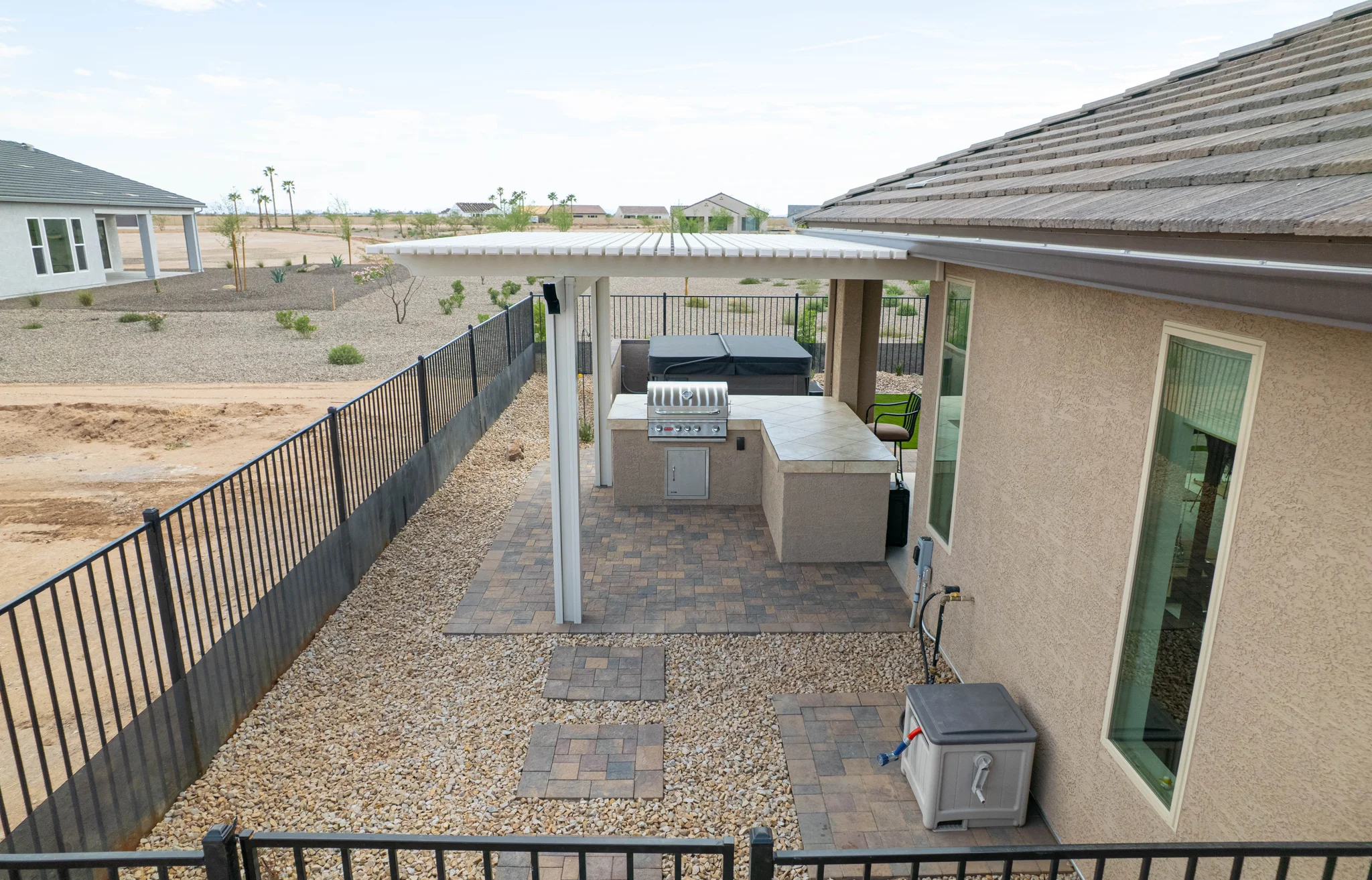 Covered backyard patio with grill, hot tub, and pergola