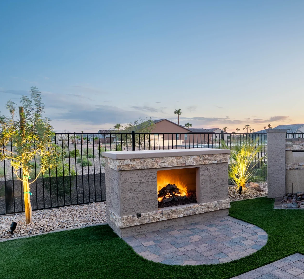 Backyard fireplace and landscaped patio at sunset