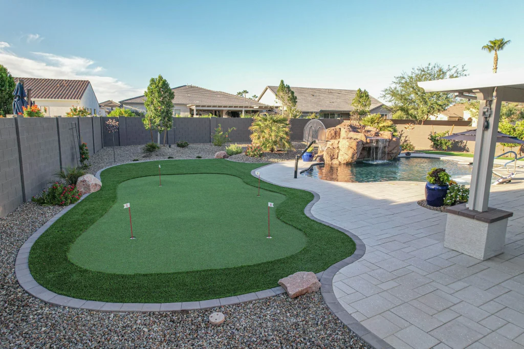 Backyard putting green beside pool and rock waterfall