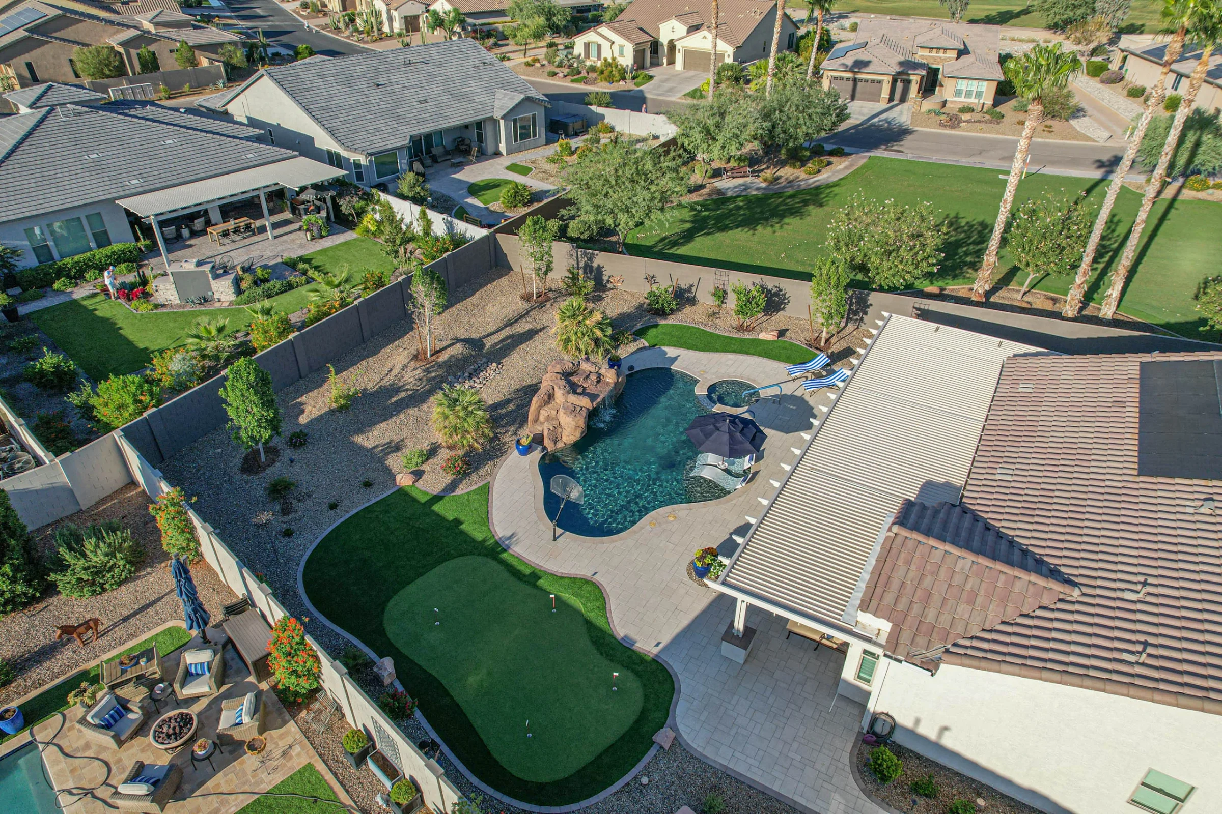 Aerial view of landscaped backyard with pool and putting green