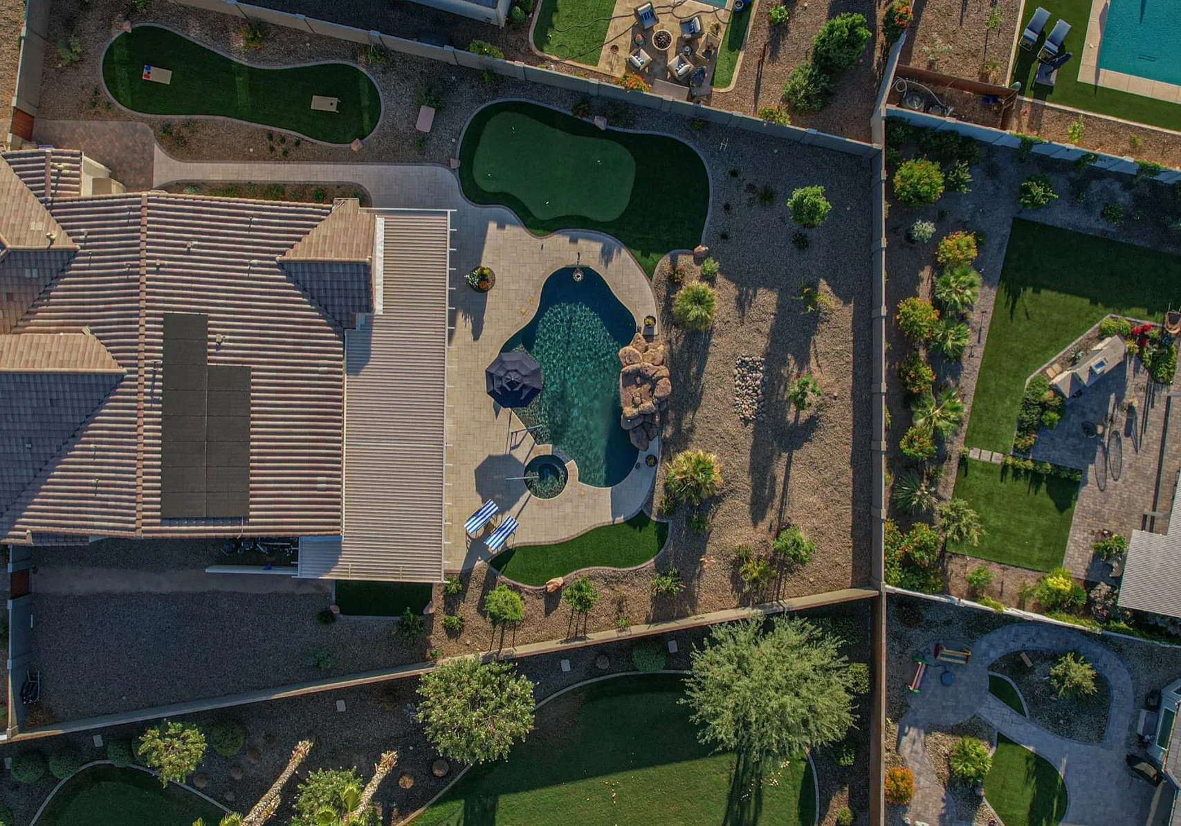Aerial view of backyard pool, patio, and putting greens