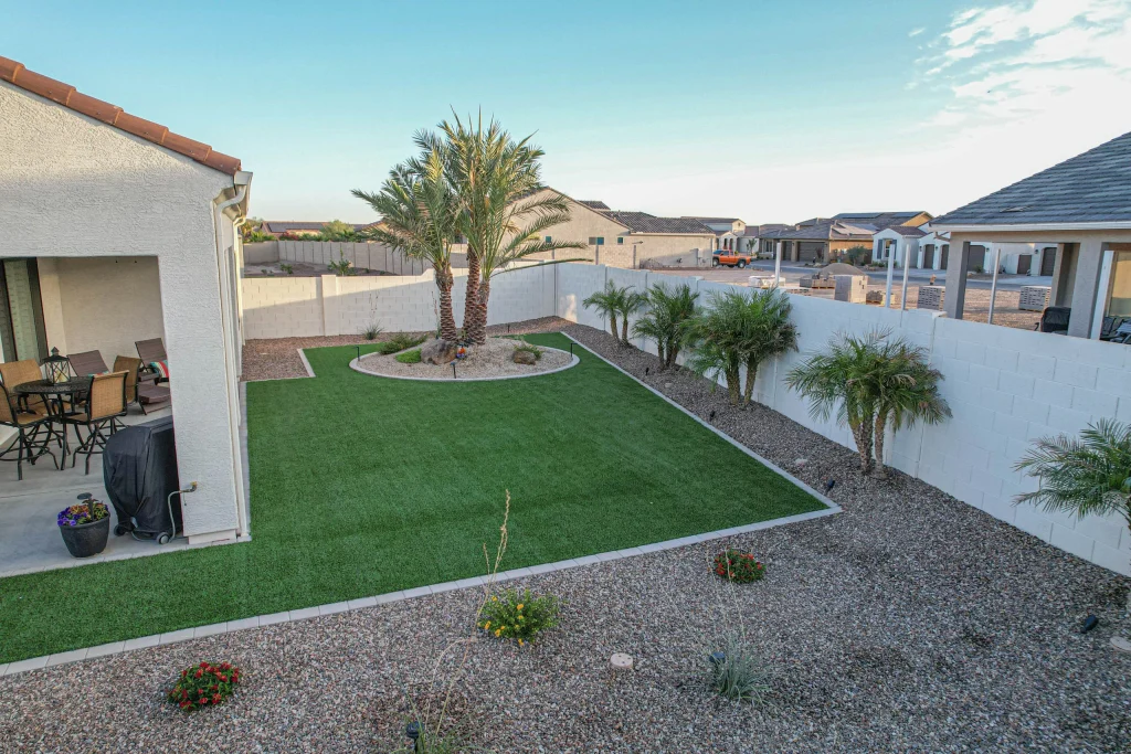 Landscaped backyard with artificial turf, palms, and covered patio