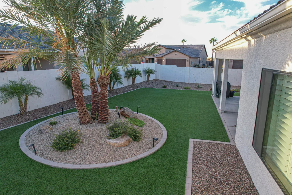 Landscaped backyard with palm trees, artificial turf, and gravel beds