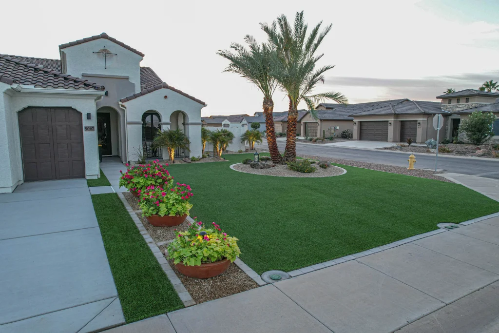 Desert home with manicured lawn, palm trees, and flower pots