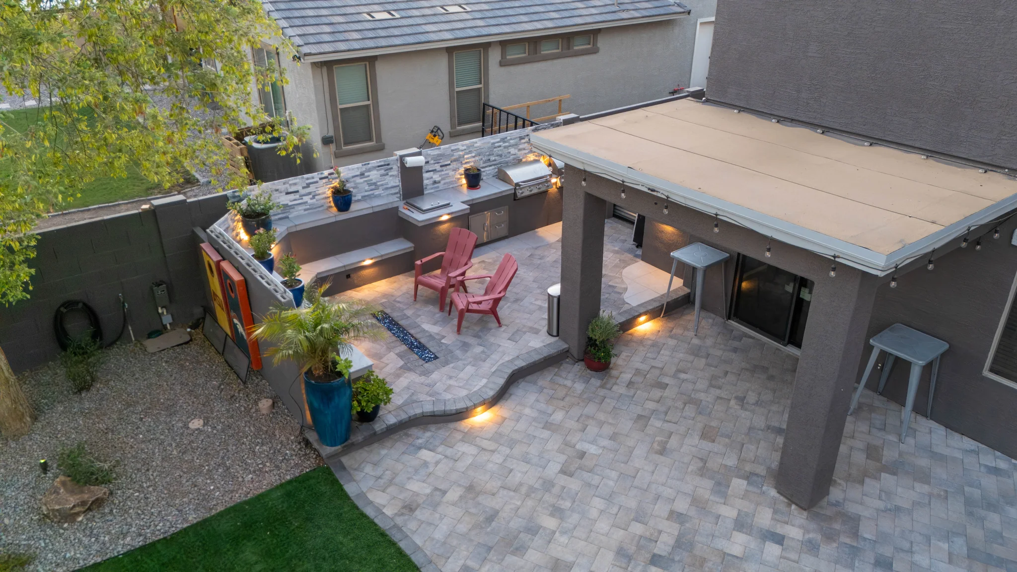 Modern backyard patio with outdoor kitchen and red chairs