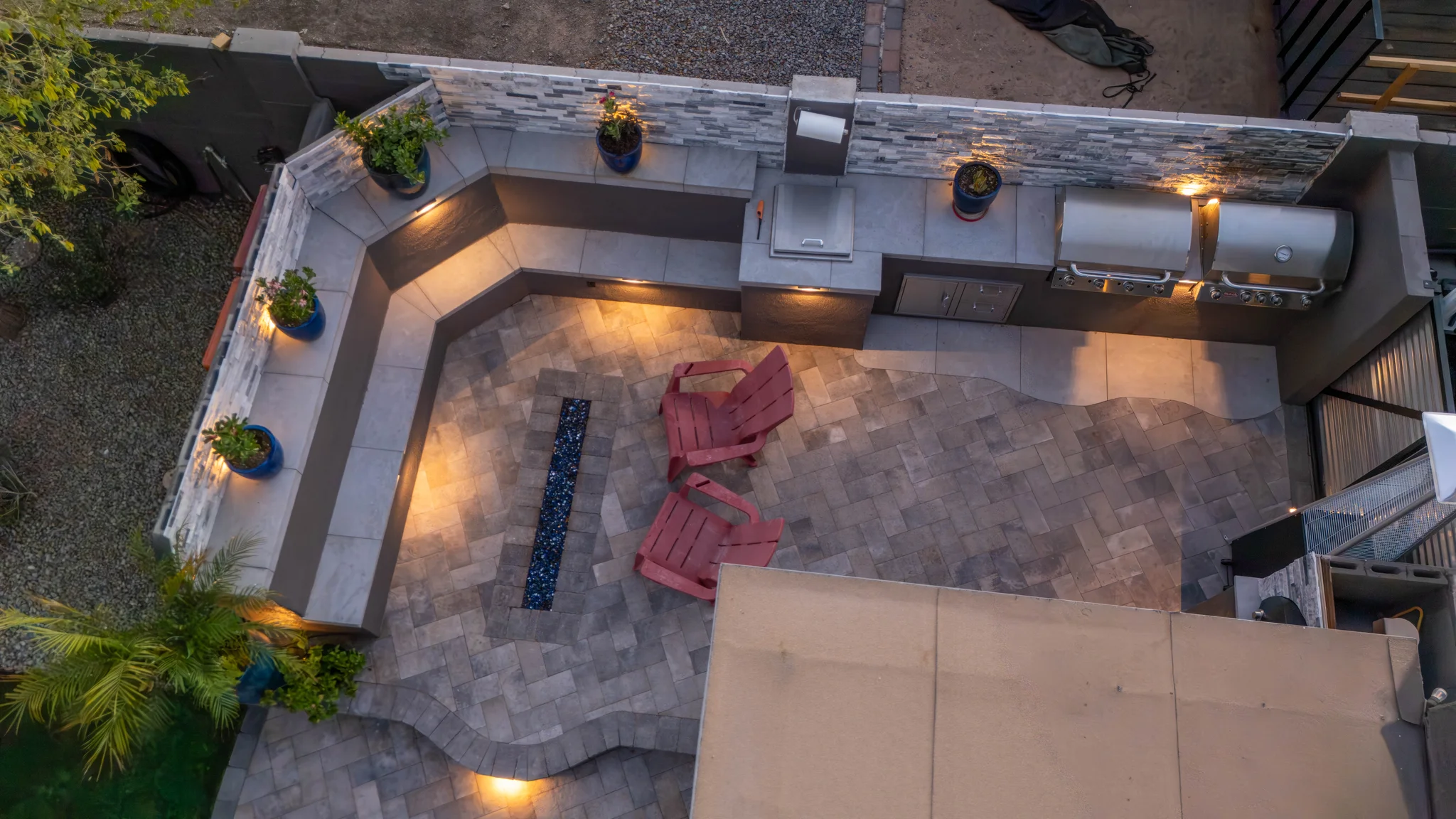 Overhead view of illuminated patio kitchen with grills and chairs