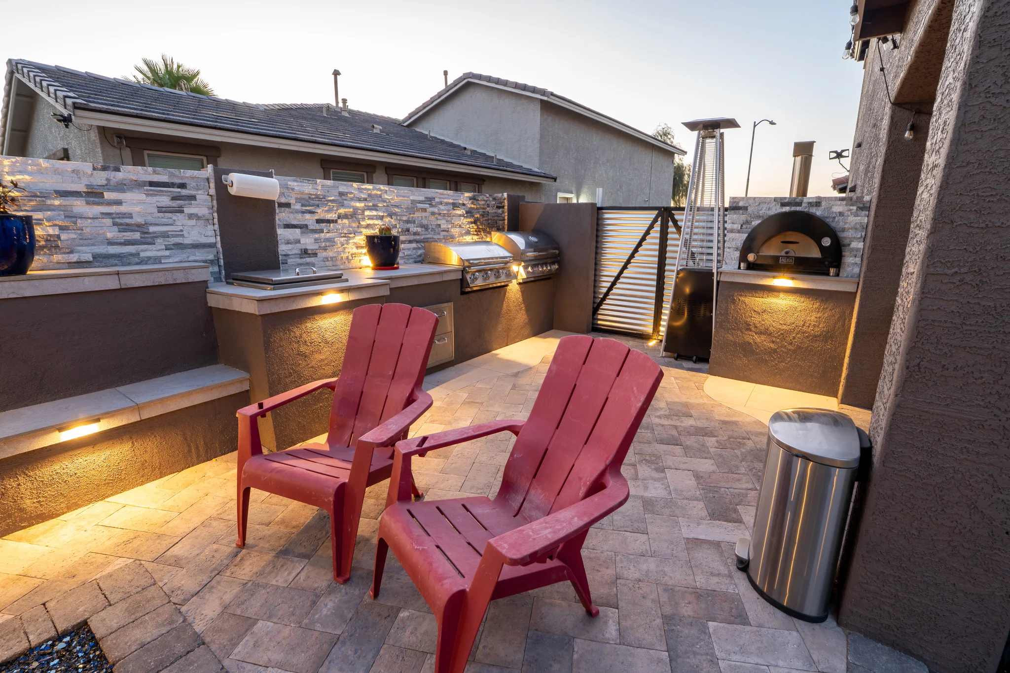 Outdoor kitchen patio with red chairs at dusk