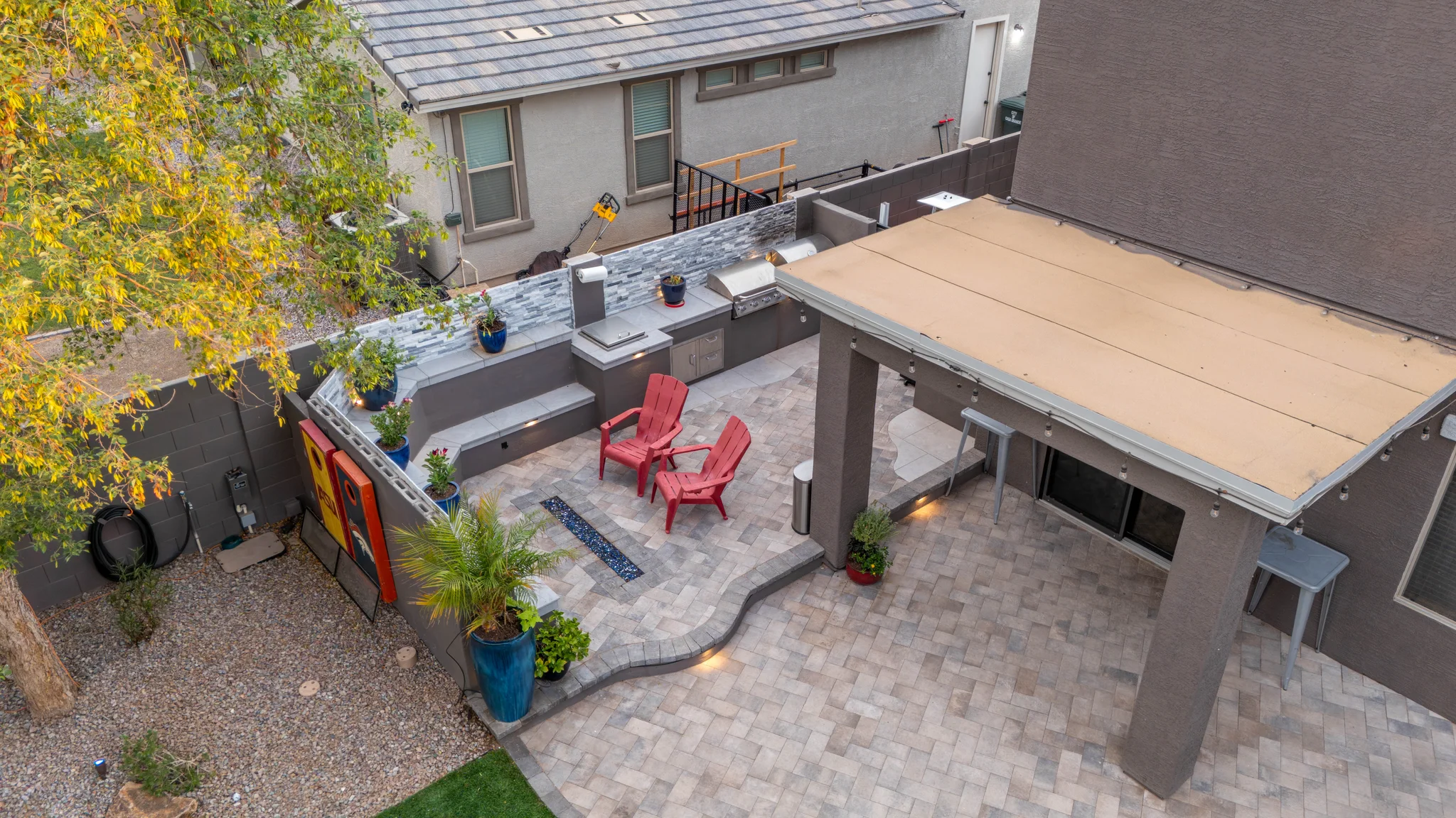 Modern backyard patio with red chairs and outdoor kitchen