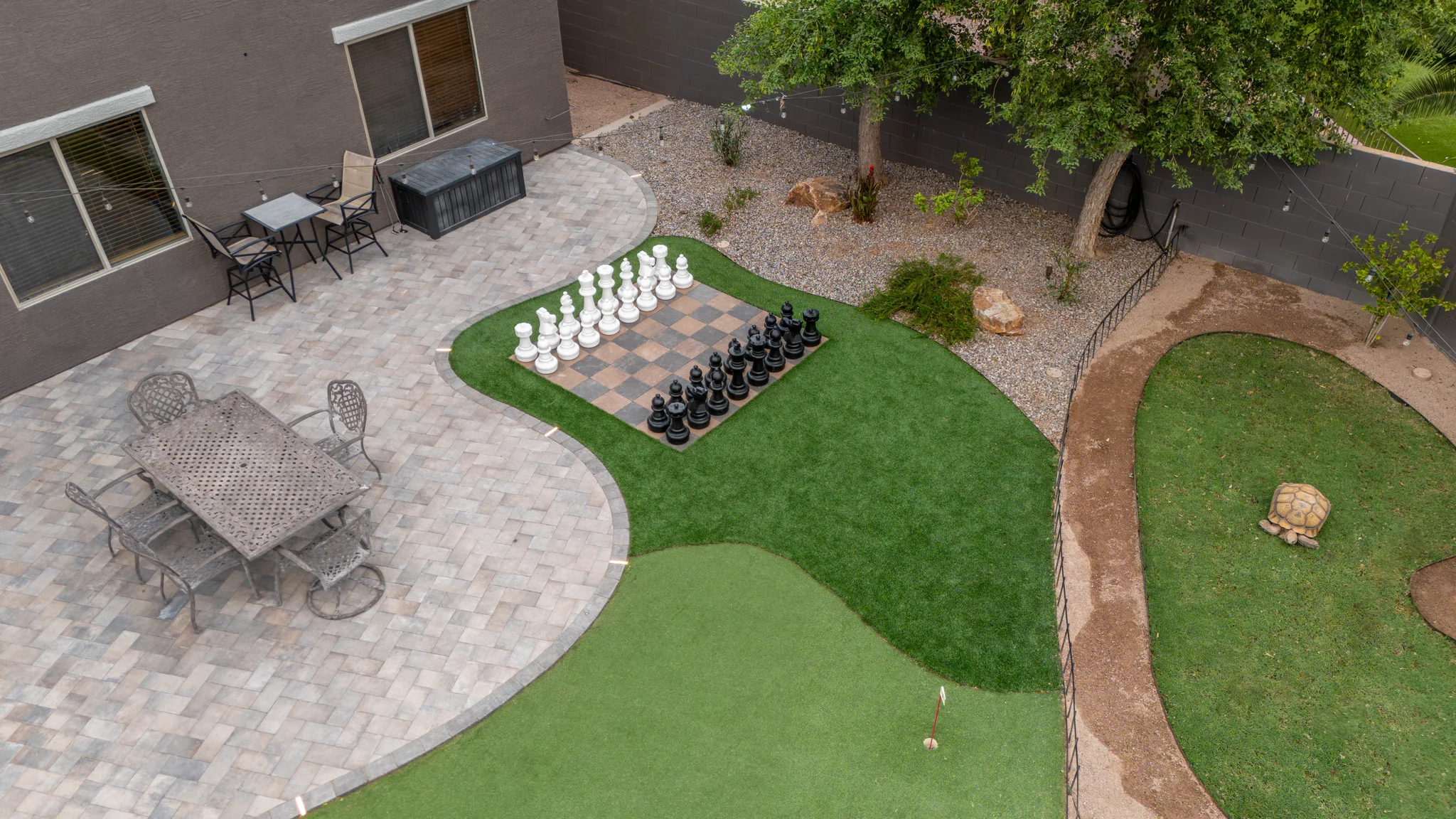 Backyard patio with giant chessboard, putting green, and tortoise