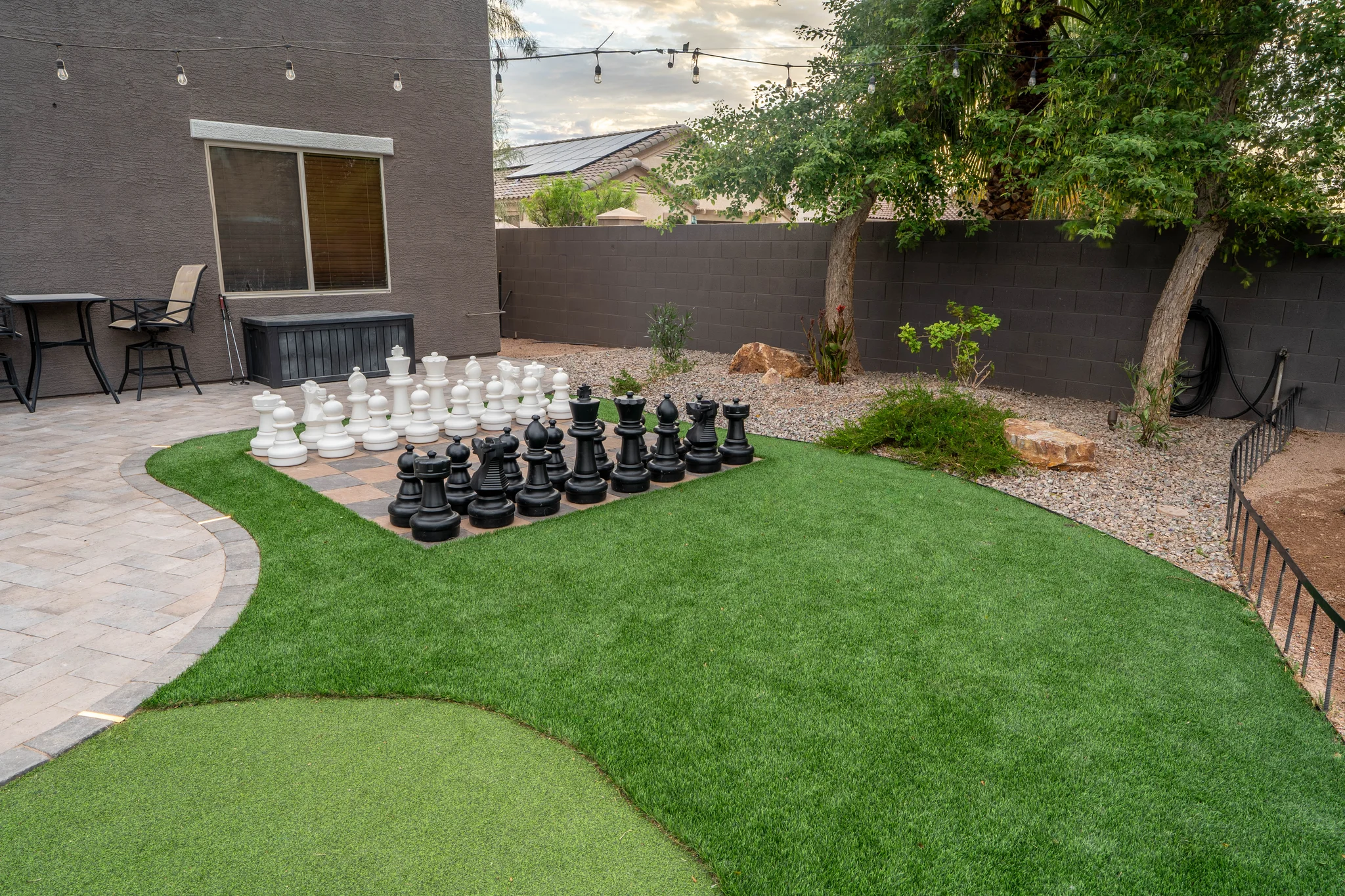 Backyard patio with oversized chess set and green lawn