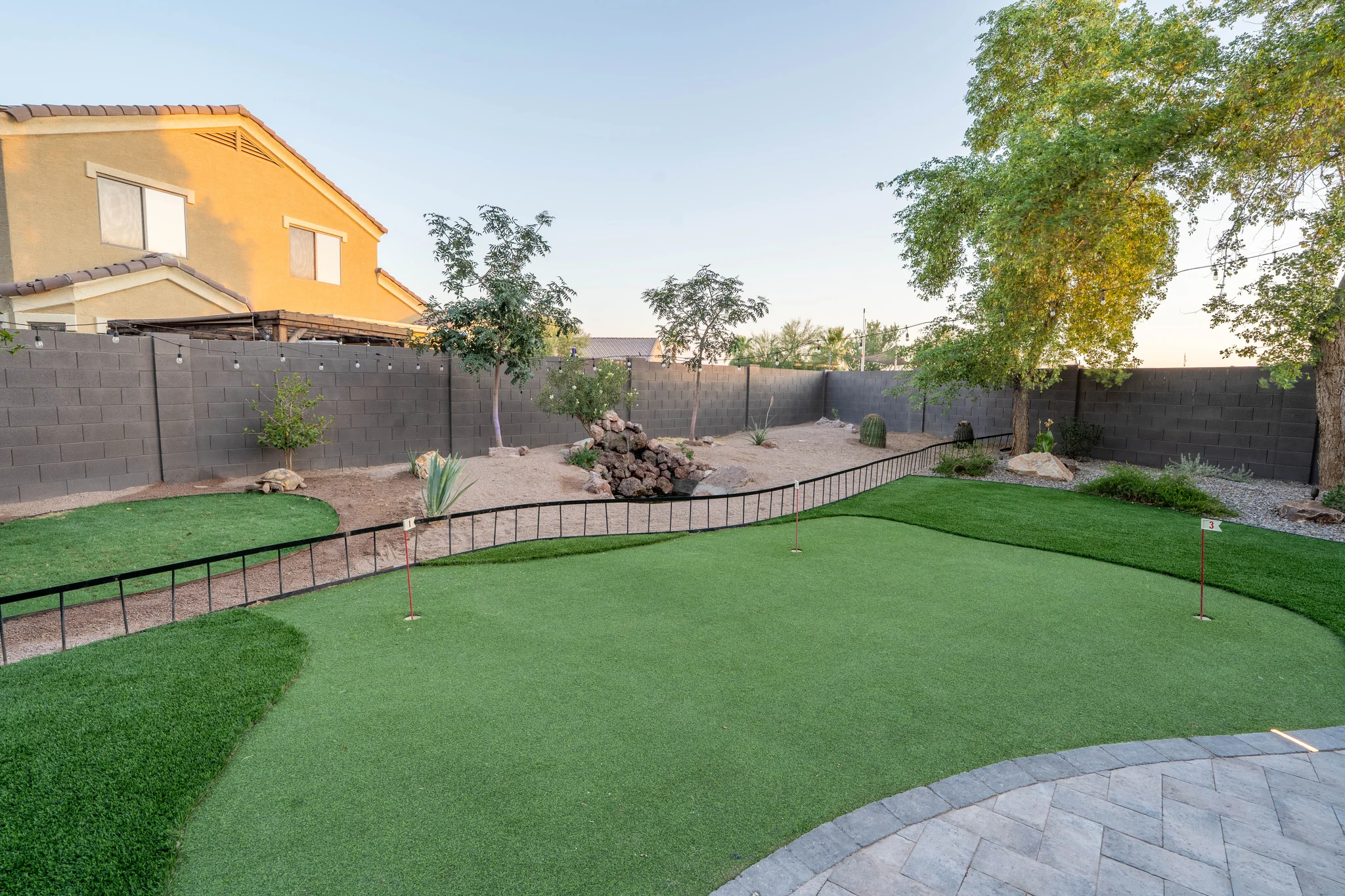 Backyard putting green with desert landscaping and mature trees