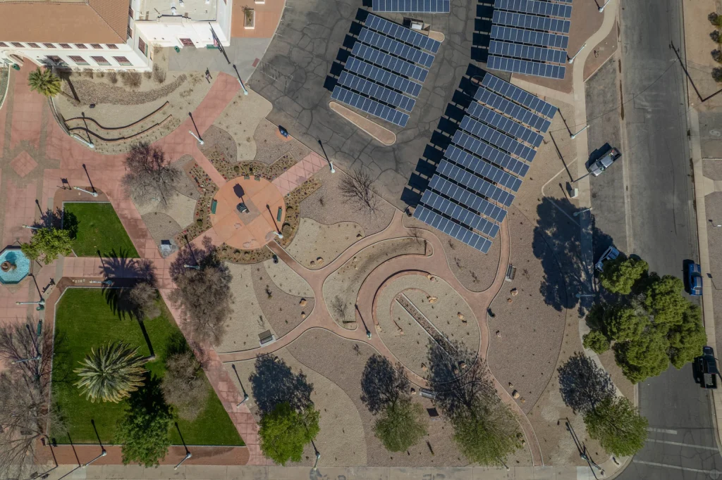 Aerial view of solar-panel parking lot beside landscaped plaza