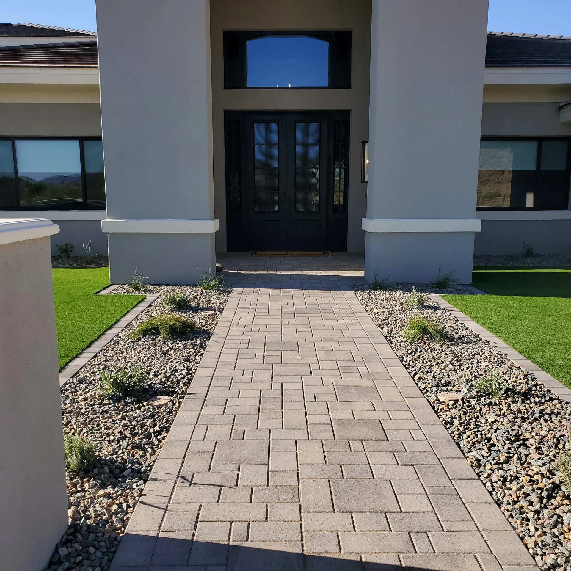 Paver walkway leading to modern home's double front doors