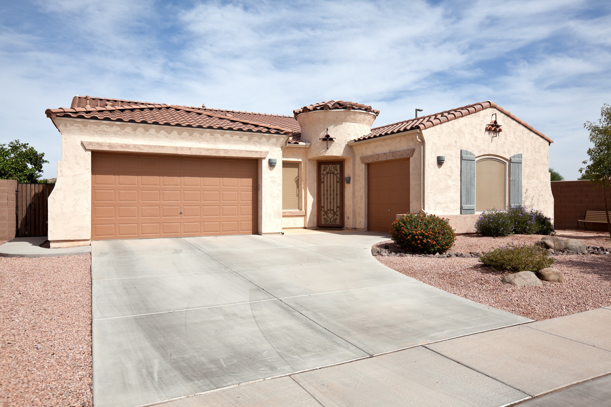 Stucco Southwestern home with tiled roof and two-car garage