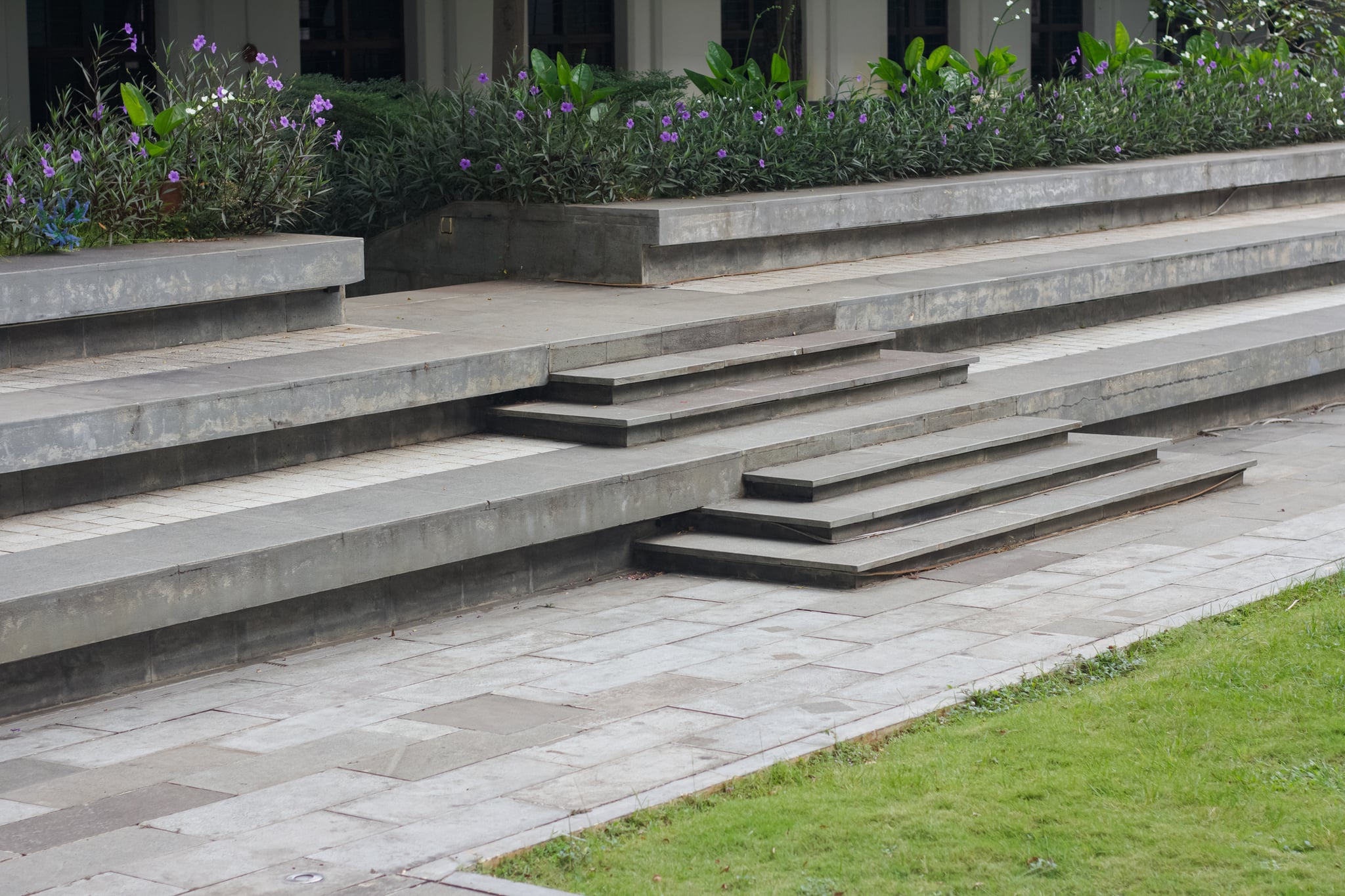 Tiered gray stone steps beside purple flower beds