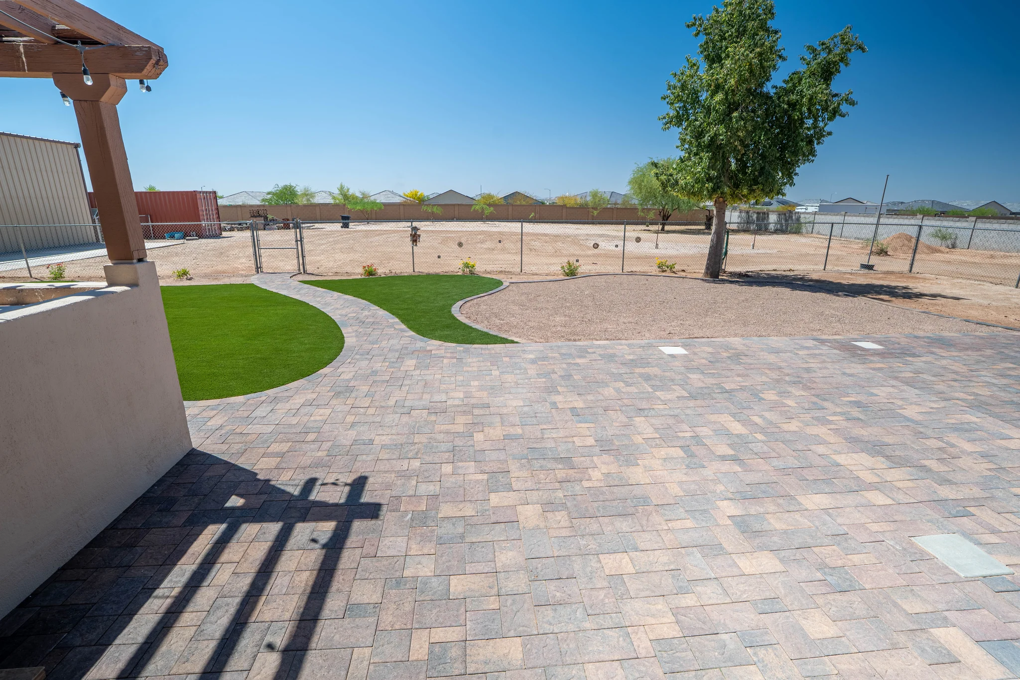 Paver patio with turf, tree, and fenced backyard