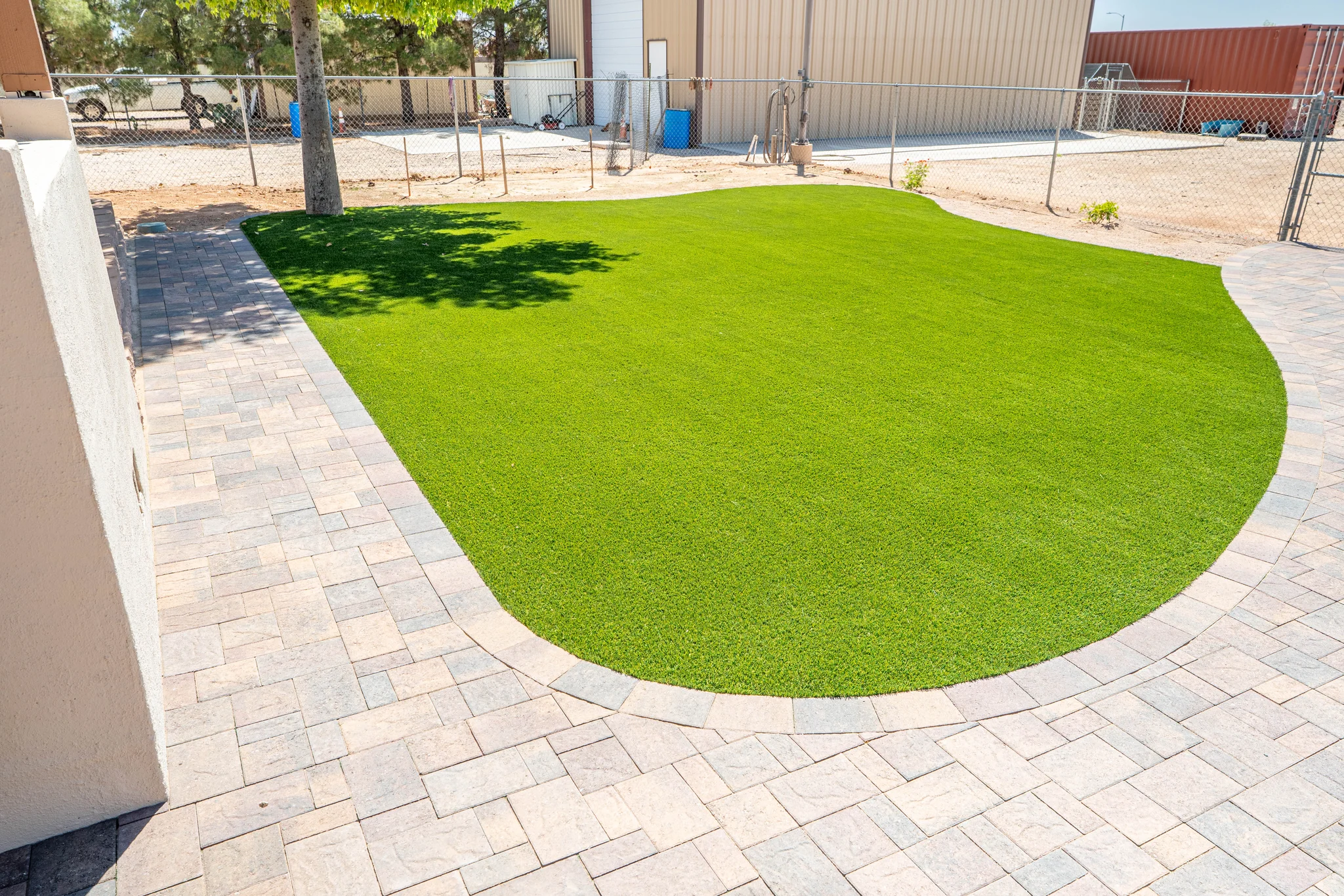 Artificial turf lawn bordered by curved stone pavers