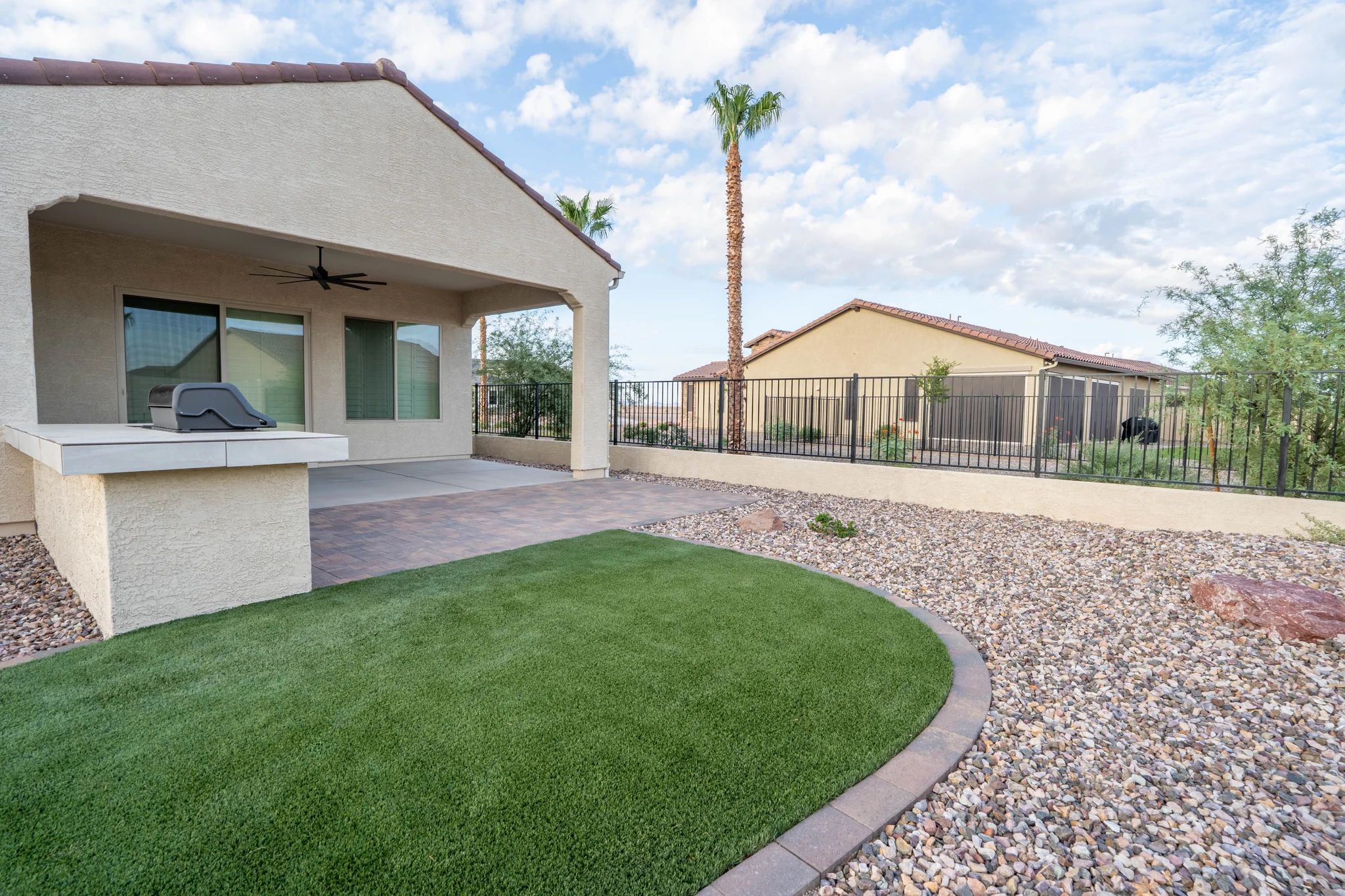 Covered patio with grill, artificial turf, and desert landscaping