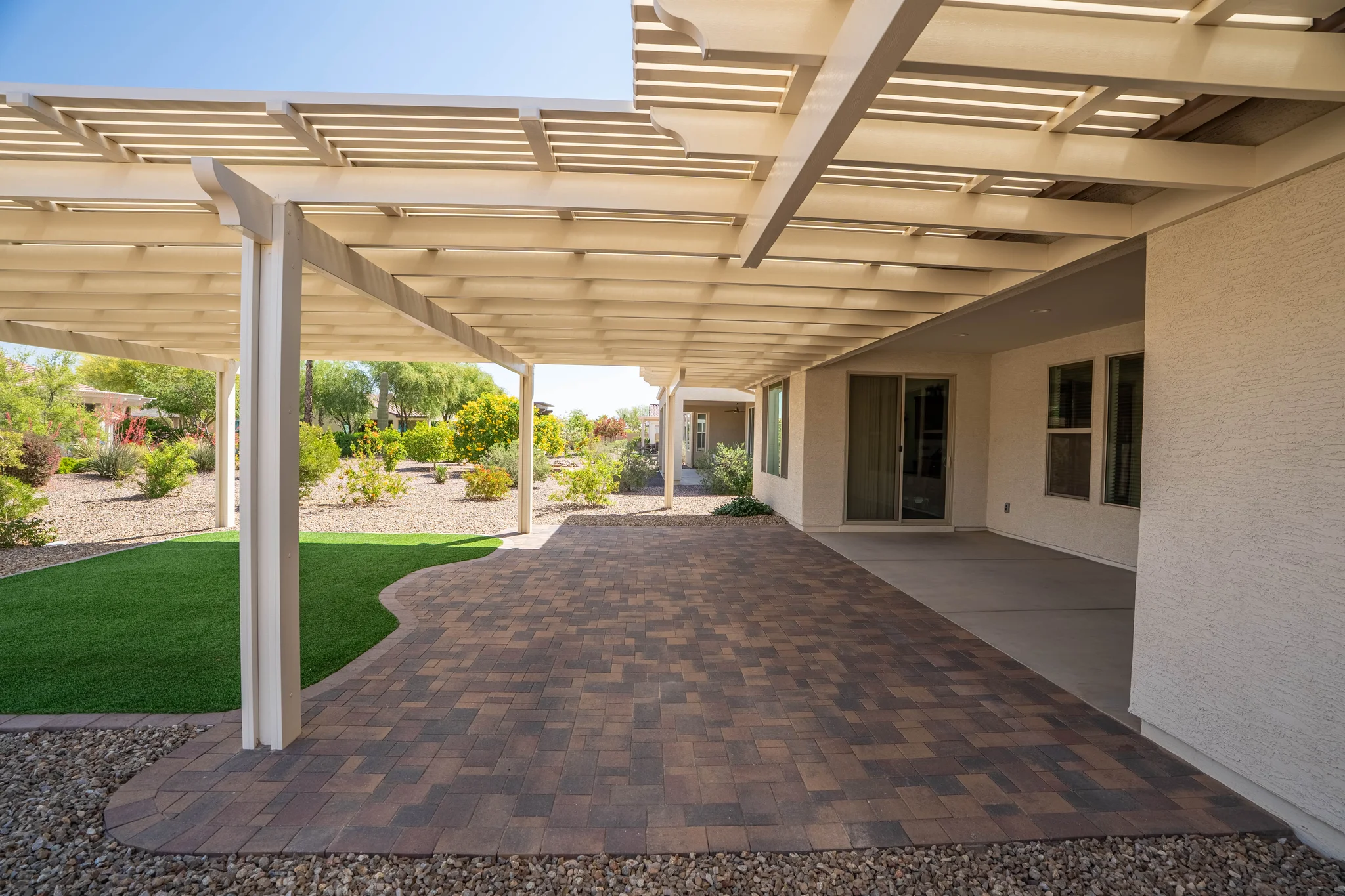 Covered backyard patio with pergola and paver flooring