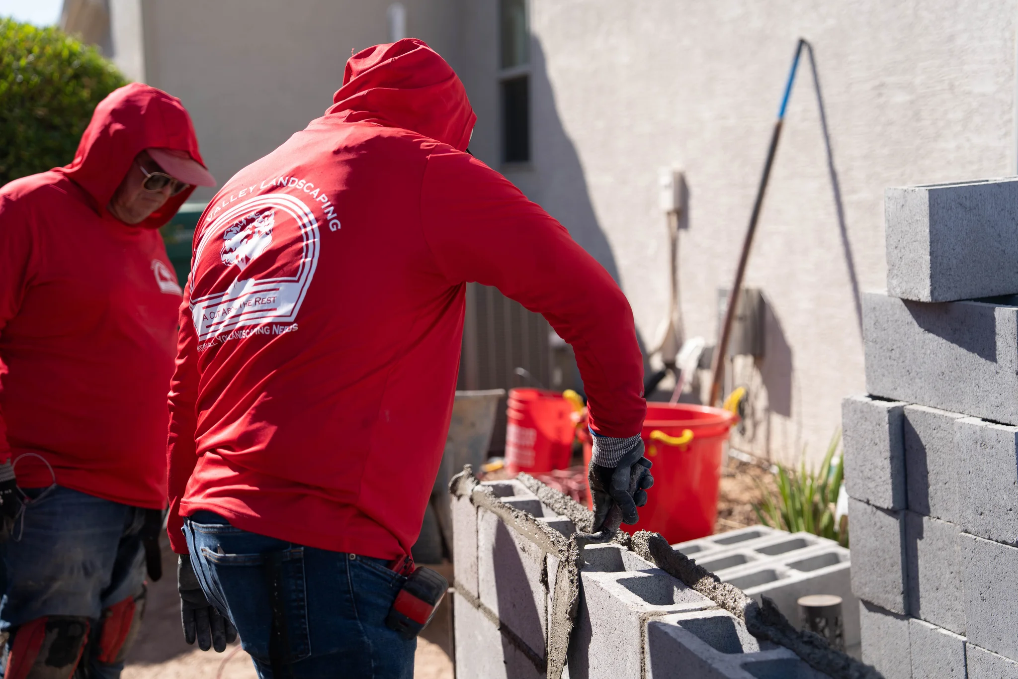 Landscapers build a cinder block wall outdoors