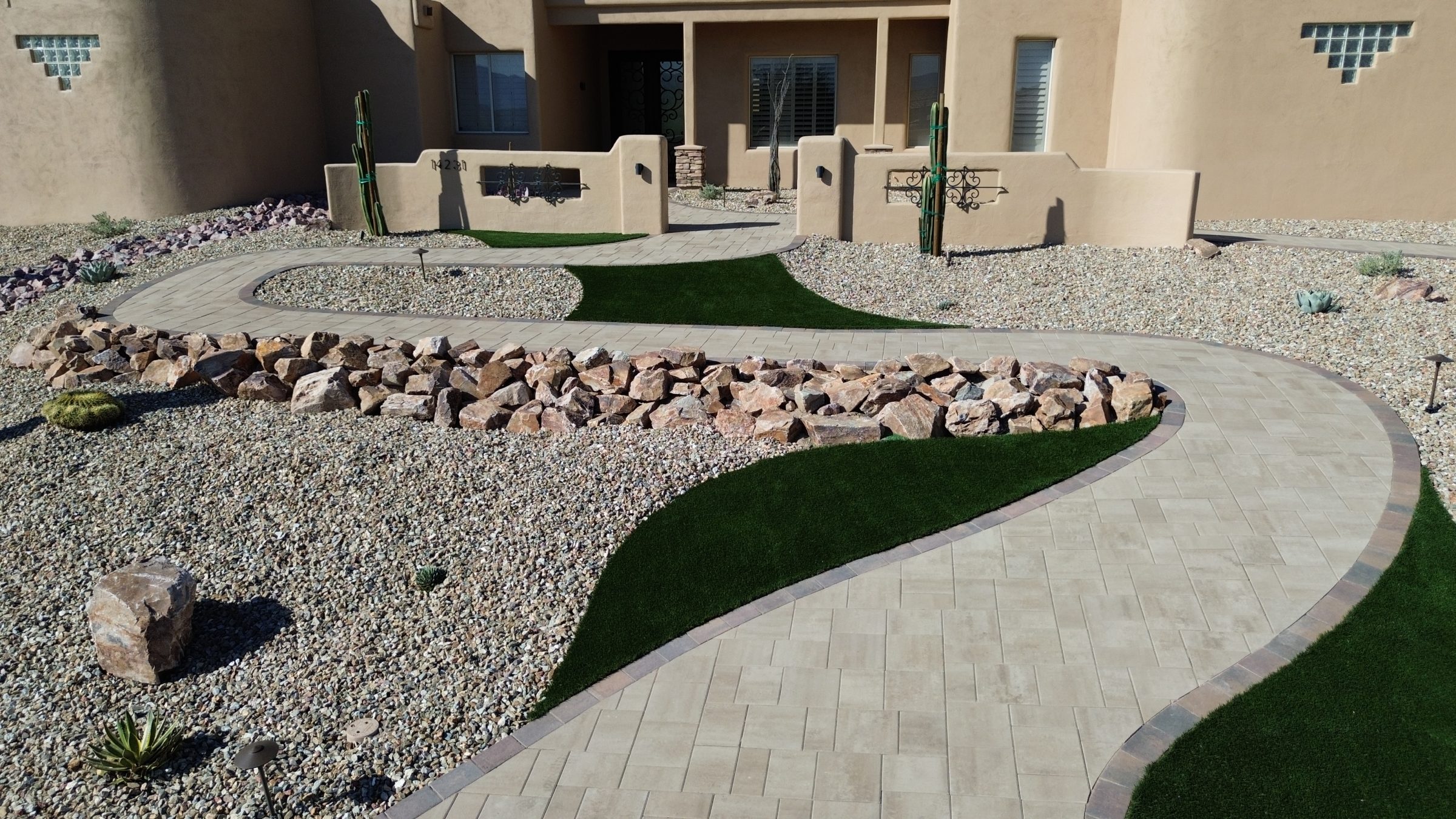 Curved paver walkway through desert-style front yard landscaping